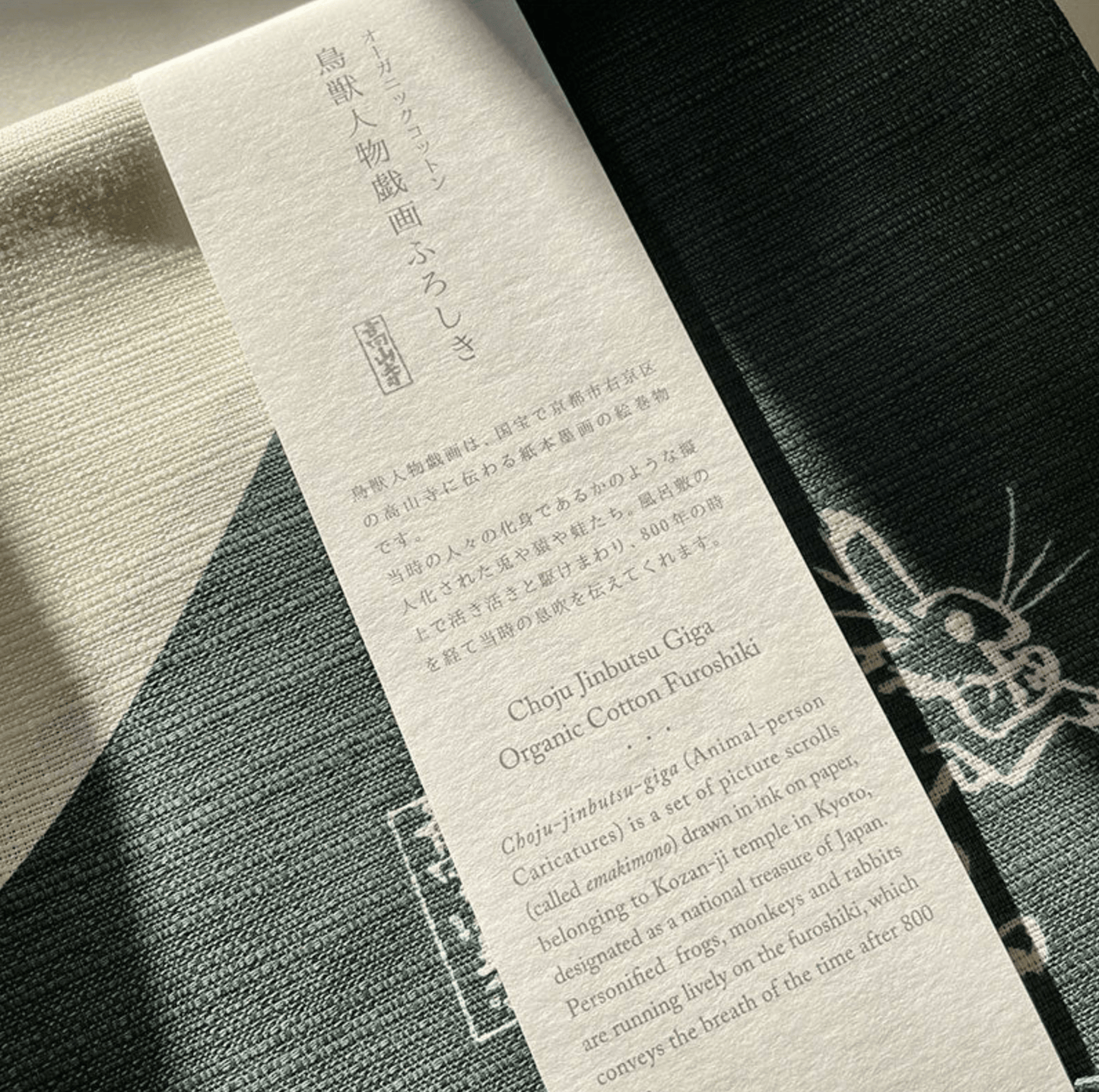 Close-up of woven organic cotton texture and product label on green Japanese medium furoshiki cloth.