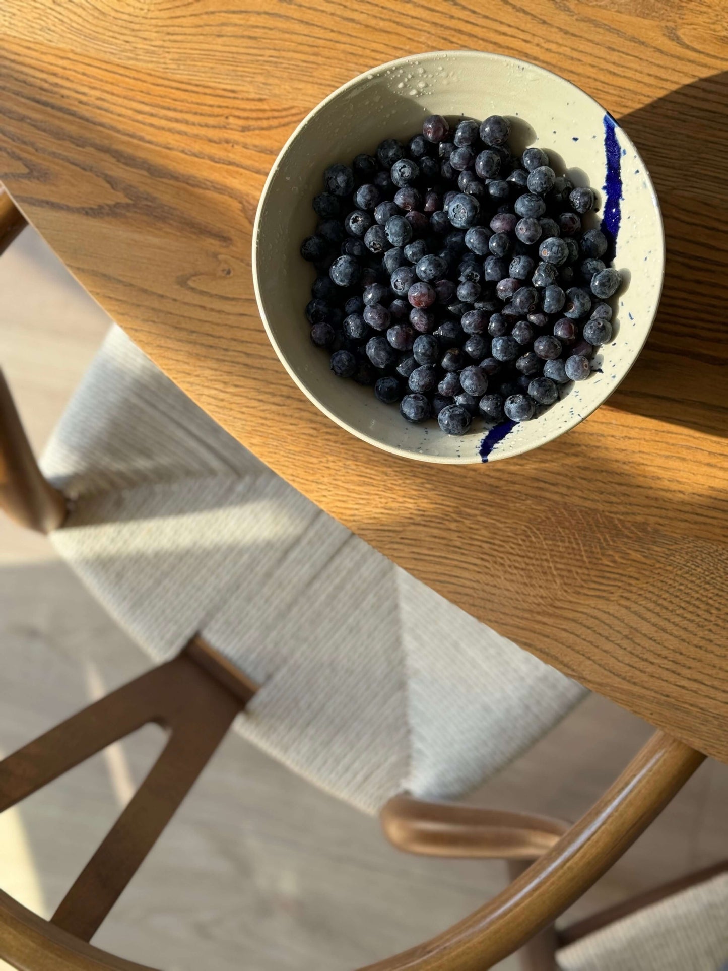 Berry Bowl from Gosu Series #03 with fresh blueberries, featuring clear glaze and cobalt blue splashes, on a wooden table.