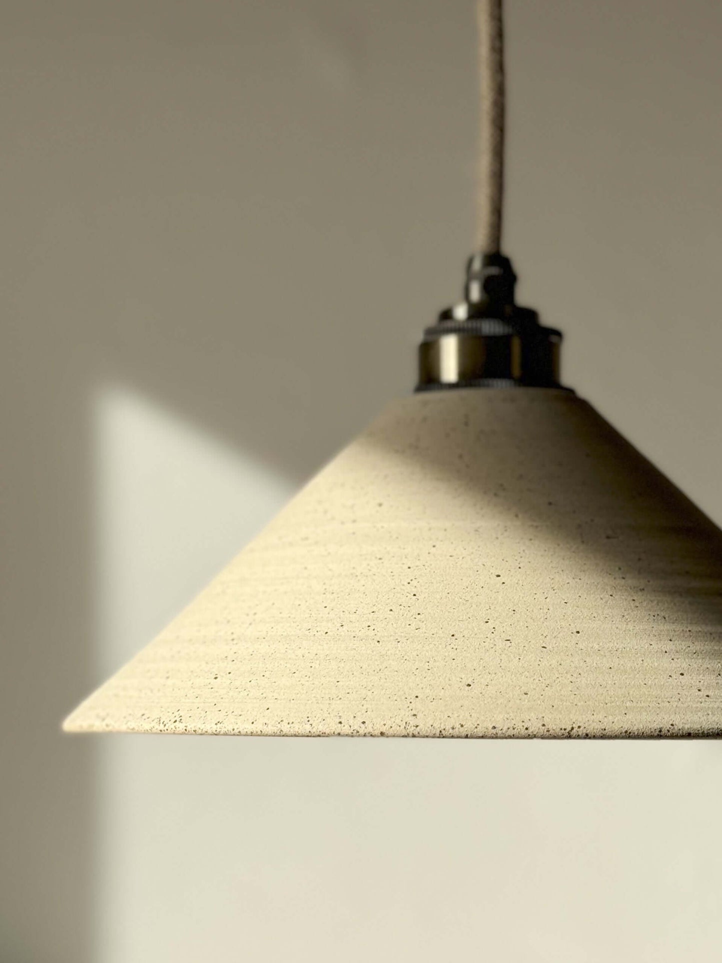 Ceramic lamp shade with unglazed exterior and clear glazed interior, creating a warm and cozy glow in a modern space.