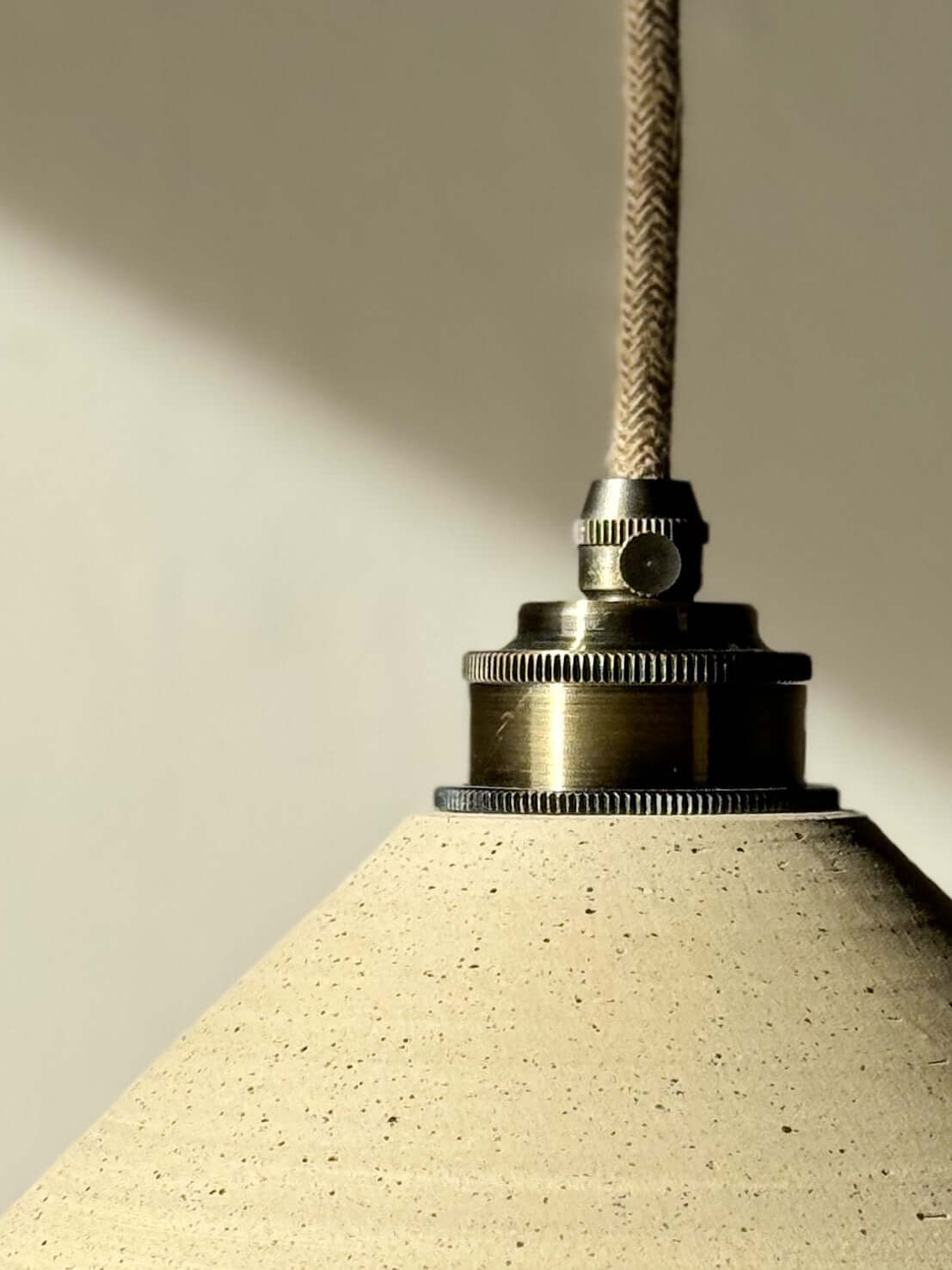 Ceramic lamp shade with matte clay exterior and clear glazed interior, featuring brass fittings, creating a warm and inviting glow.