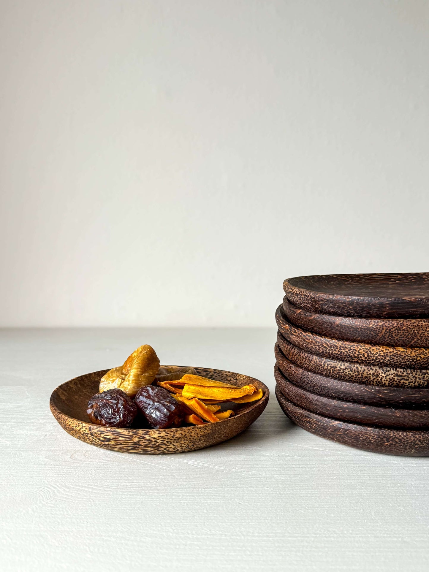 Handcrafted coconut wood side plates with unique patterns, featuring dried fruits, adding natural elegance to table settings.