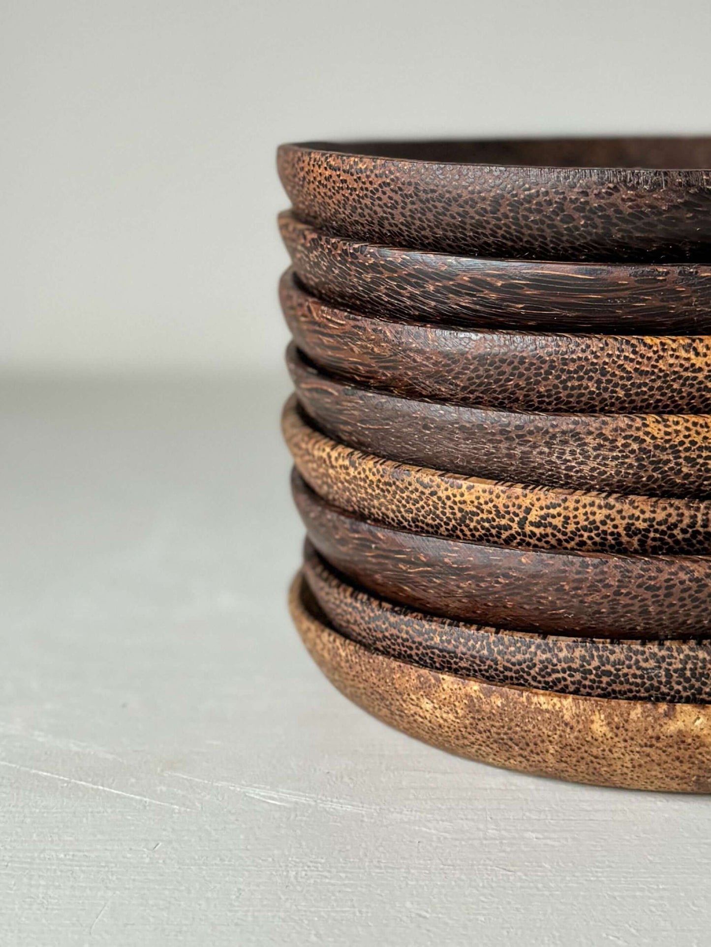 Stack of handcrafted coconut wood side plates with unique grain patterns, ideal for adding a natural touch to your dining table.
