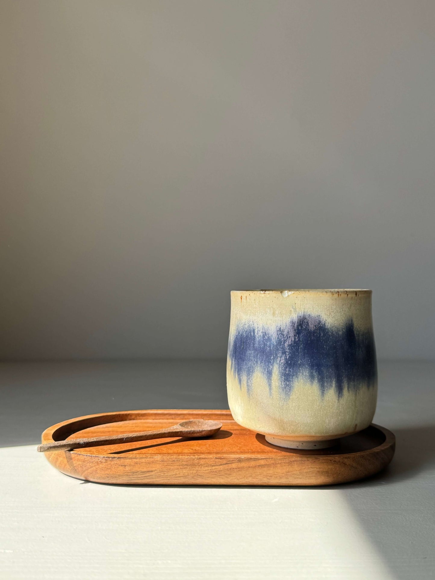 Cobalt blue and moonstone glaze flower yunomi cup on a wooden tray
