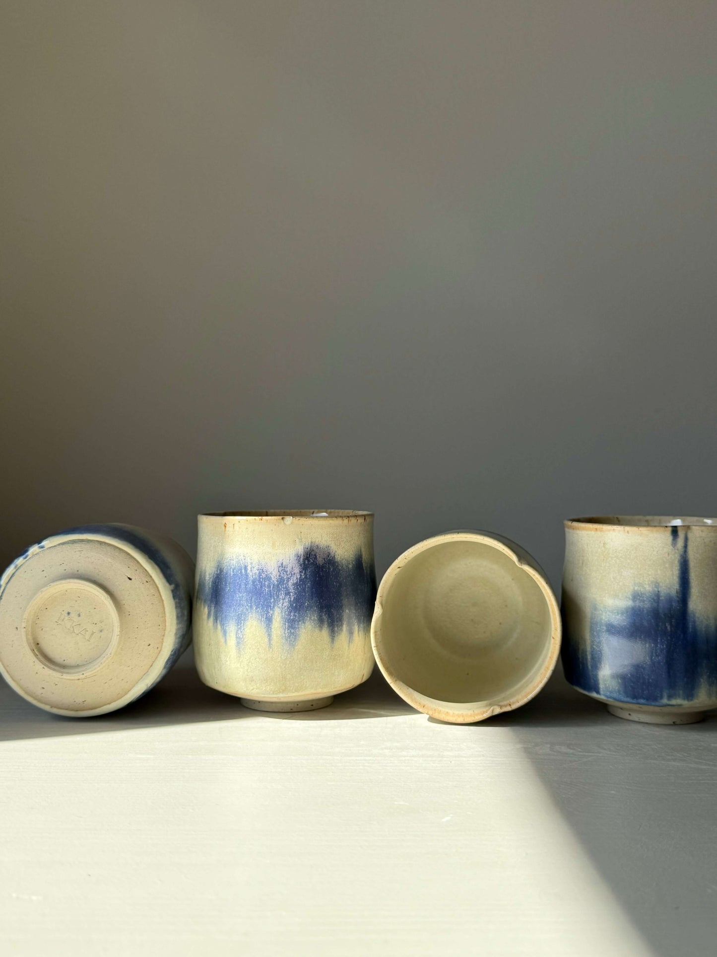 Four handmade flower yunomi cups in cobalt blue and moonstone glaze, showcasing their unique shape and glaze details.