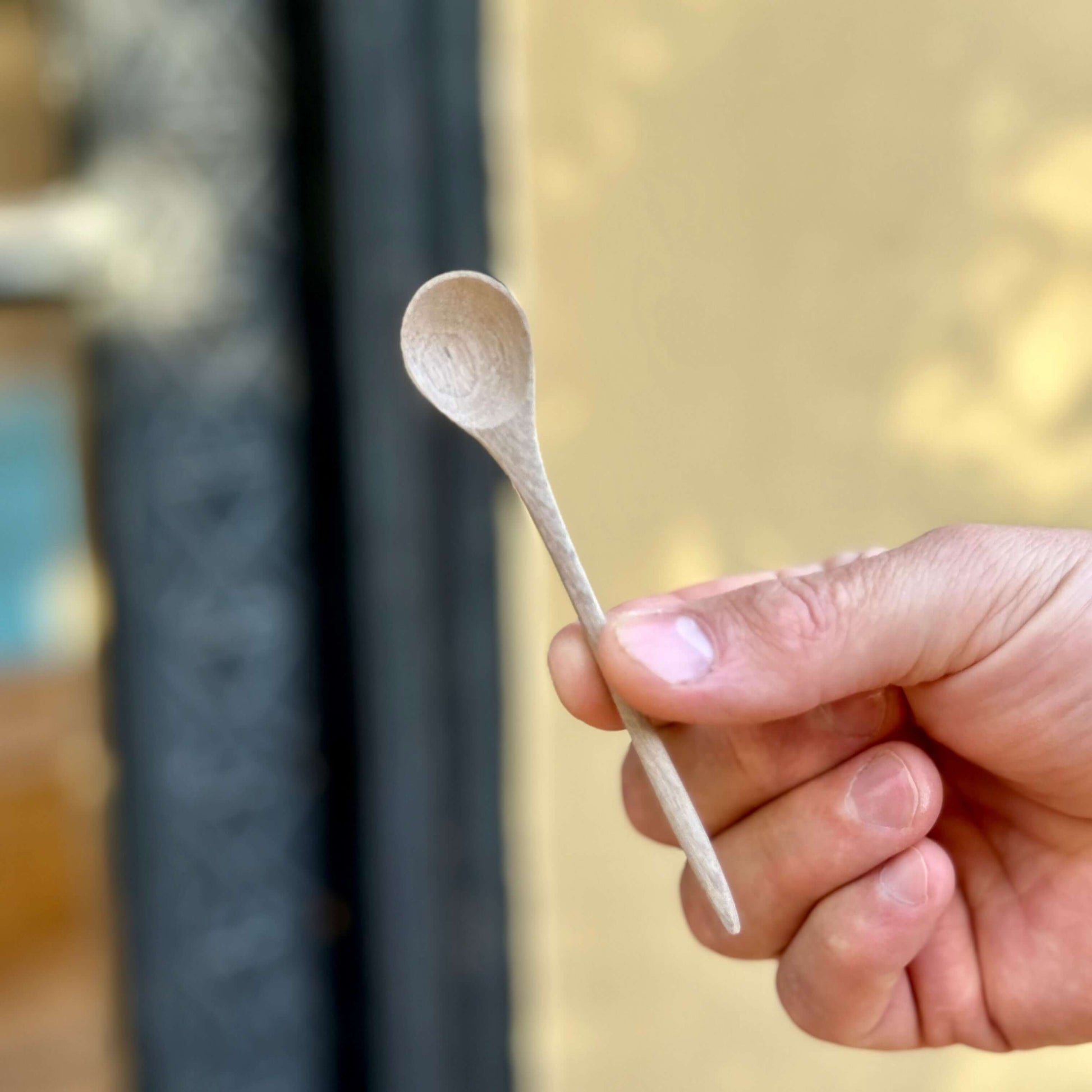 Hand-Carved Walnut Tea Spoon held by hand, showcasing handmade ceramic charm from Marrakech.