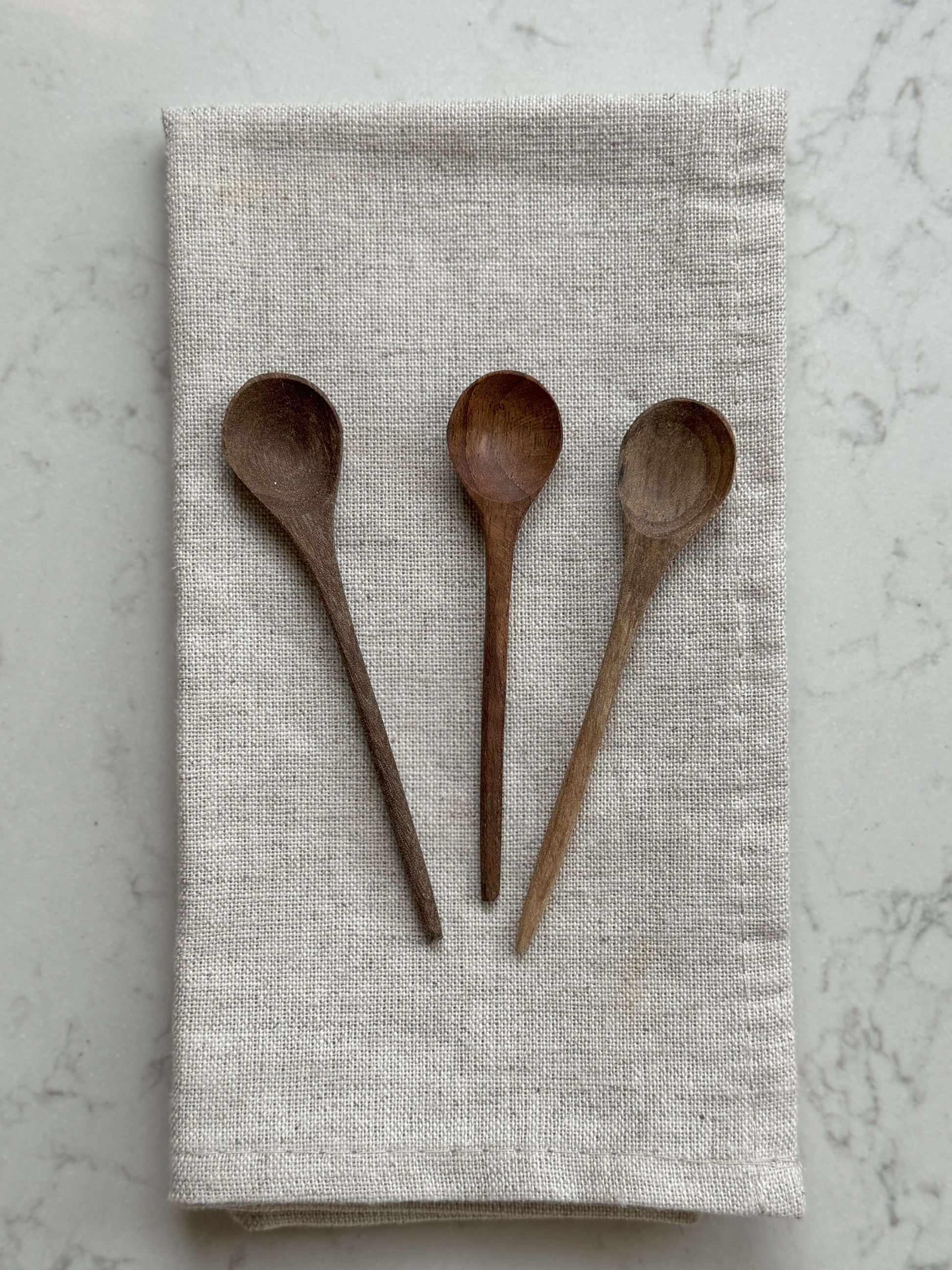 Hand-Carved Walnut Tea Spoons displayed on a linen cloth, showcasing artisanal craftsmanship and handmade charm.