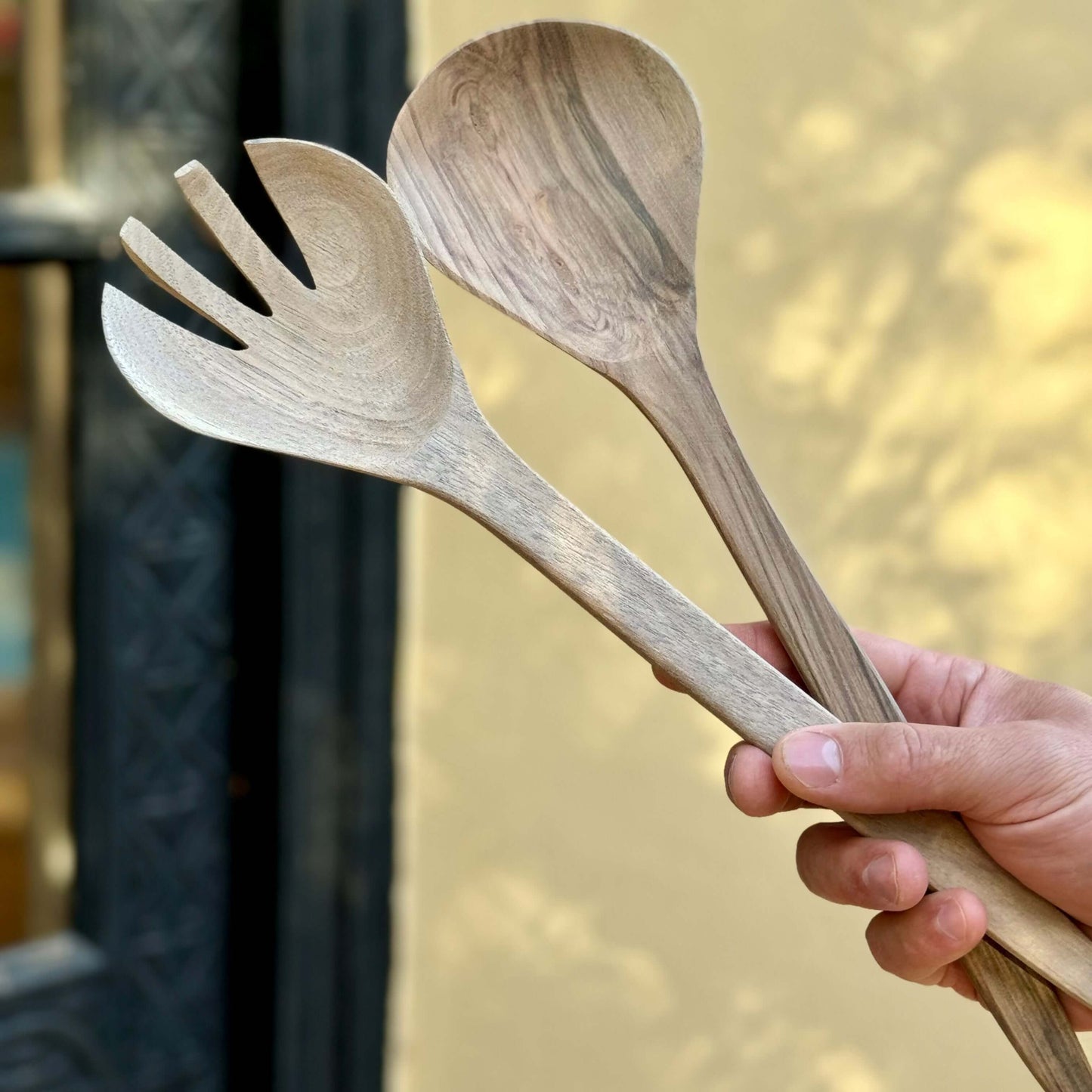 Hand holding Hand-Carved Walnut wood Salad Serving Set with unique grain pattern, perfect for salads, pasta, or handmade ceramic dishes.