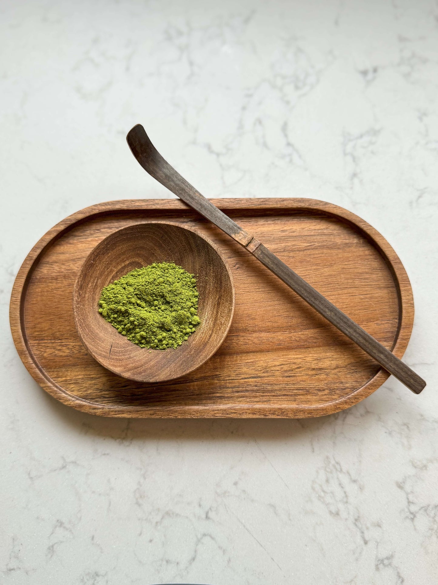 Hand-carved walnut wood bowl with matcha powder on a wooden tray, showcasing unique grain and Marrakech craftsmanship.