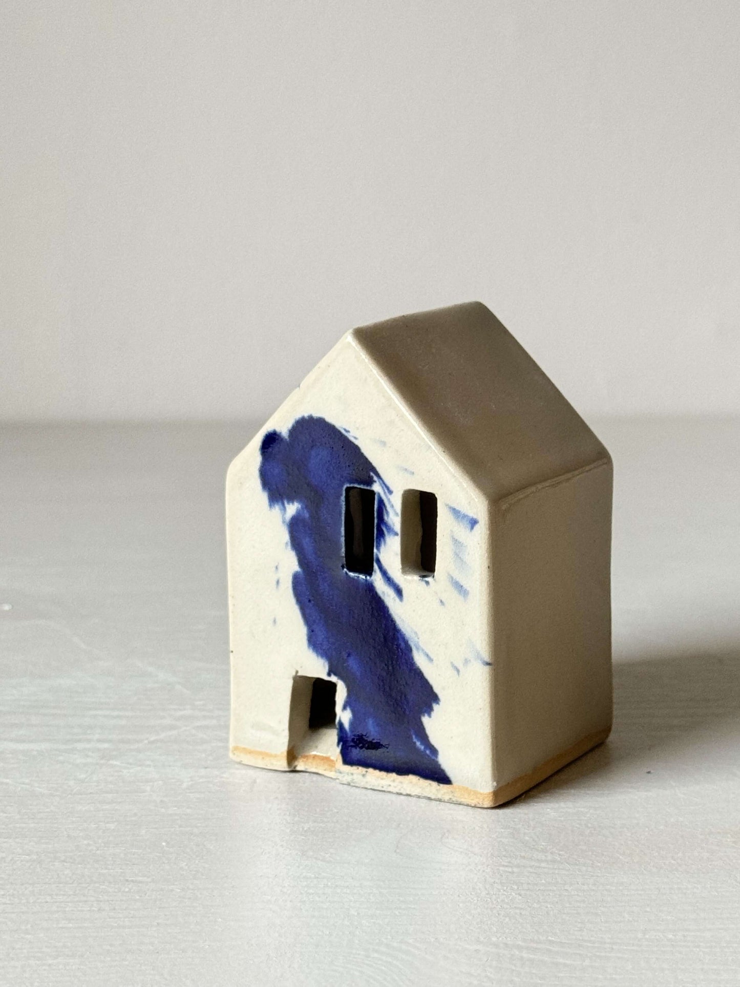 Handbuilt ceramic house with cobalt blue splashes, part of the Gosu Series, adding a quirky Dutch vibe to any mantel or shelf.