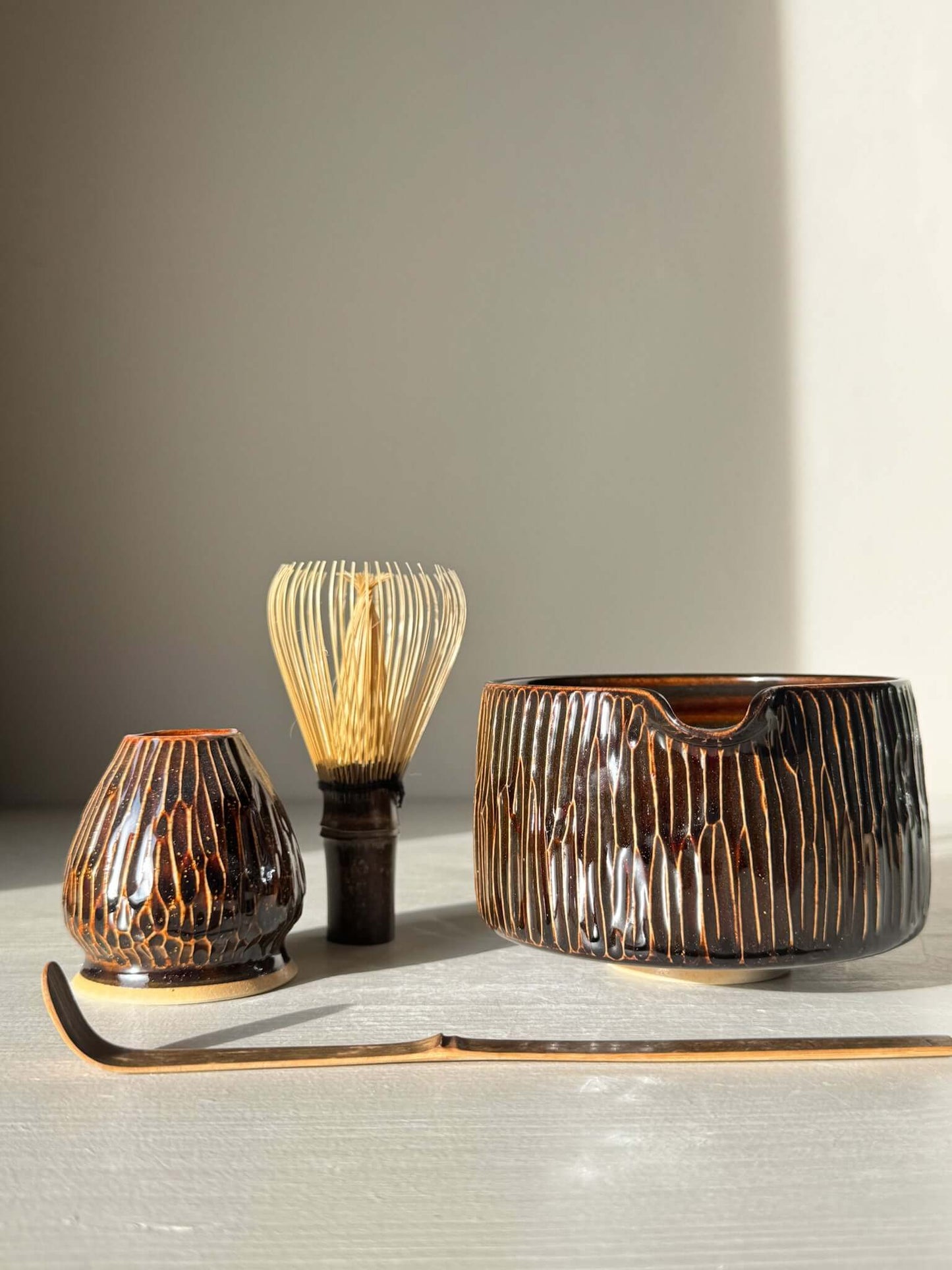 Matcha Bowl Spout – Kinsei #01 with carved design and glaze, complete with whisk and scoop, bathed in sunlight.