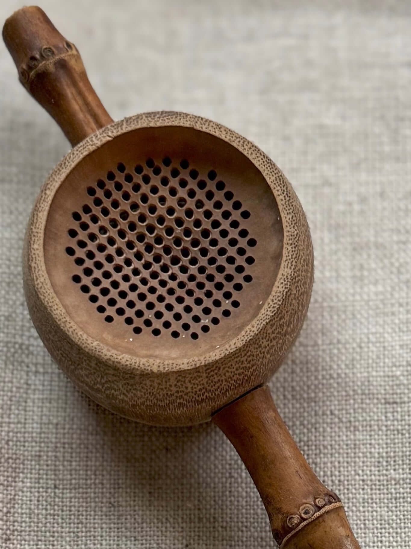 Bamboo Tea Strainer with rustic charm, ideal for straining tea, handmade look next to ceramic mugs, lightweight and durable bamboo accessory.