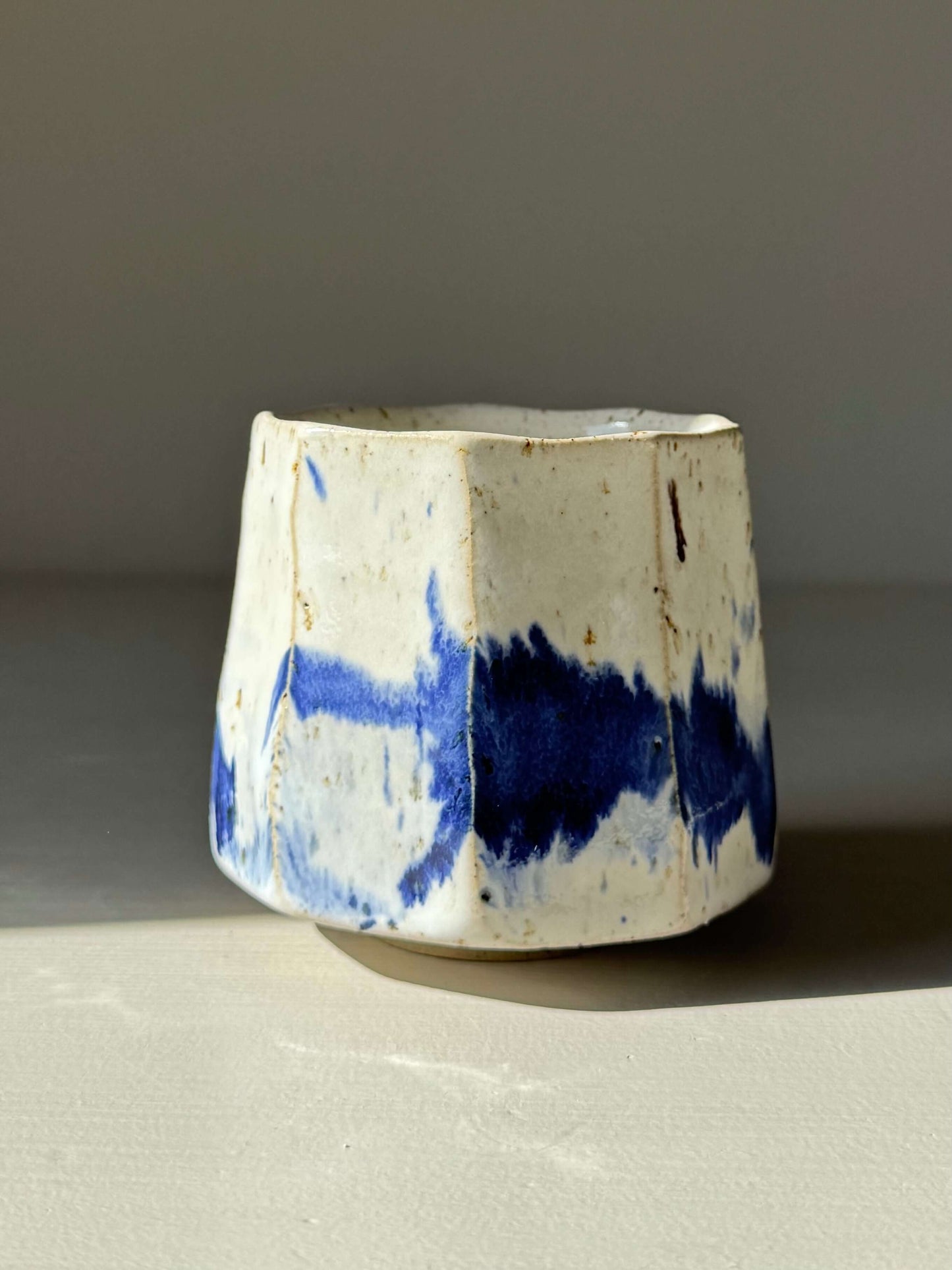 Handmade ceramic Faceted Cup – Cobalt Blue & Glossy White #01 with unique angles and blue splashes.