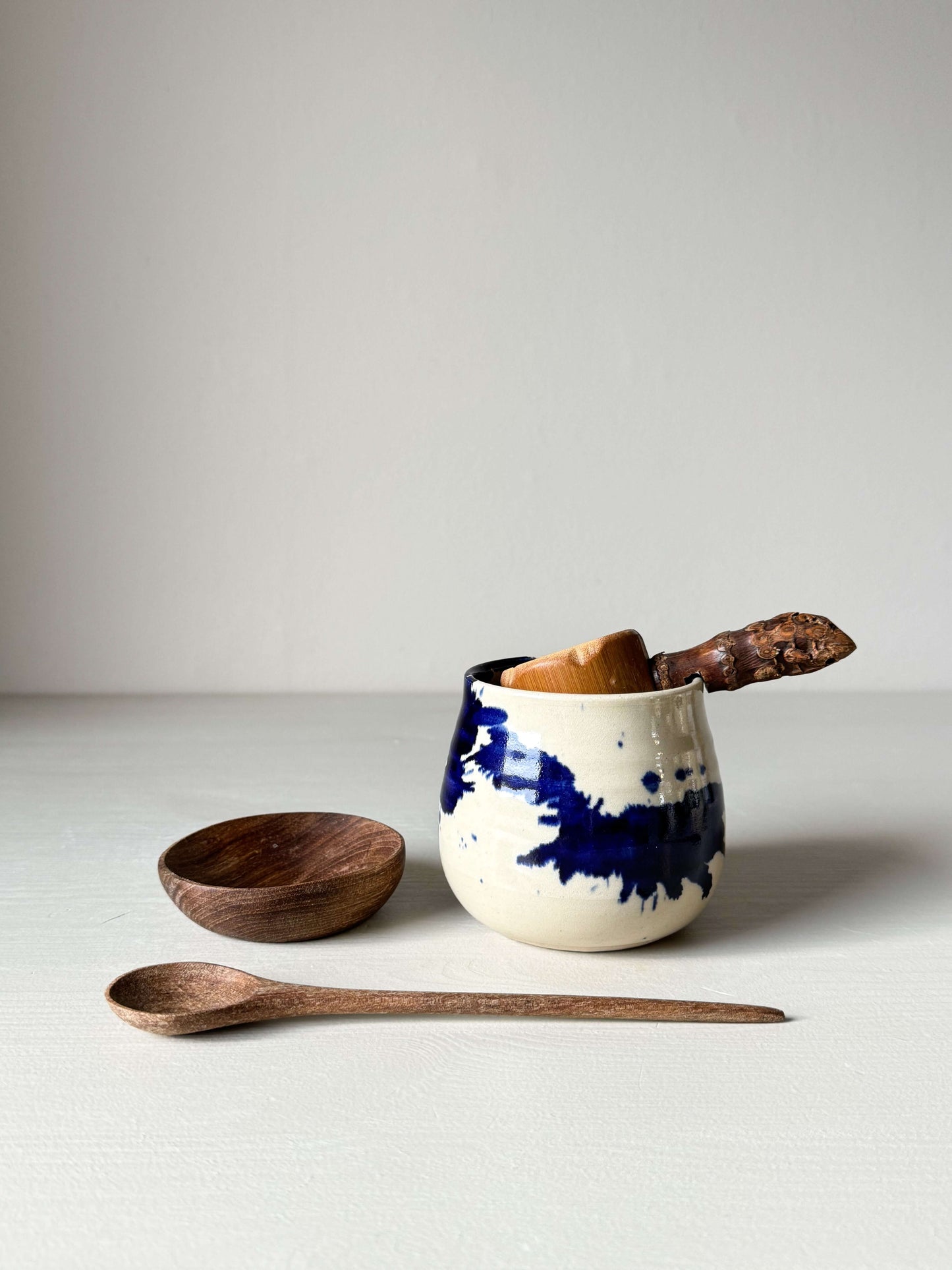 Small Walnut Wood Bowls with handmade ceramic cup and wooden spoon on a table.