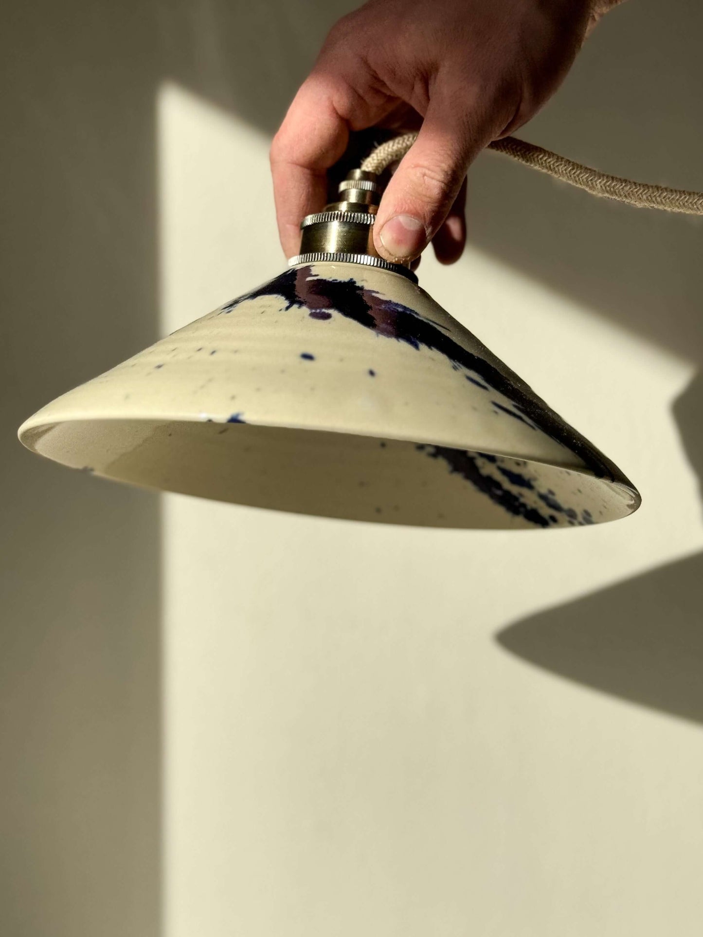 Handmade ceramic lamp shade from the Gosu Series, featuring unique cobalt blue splashes and a glossy finish, held by hand.