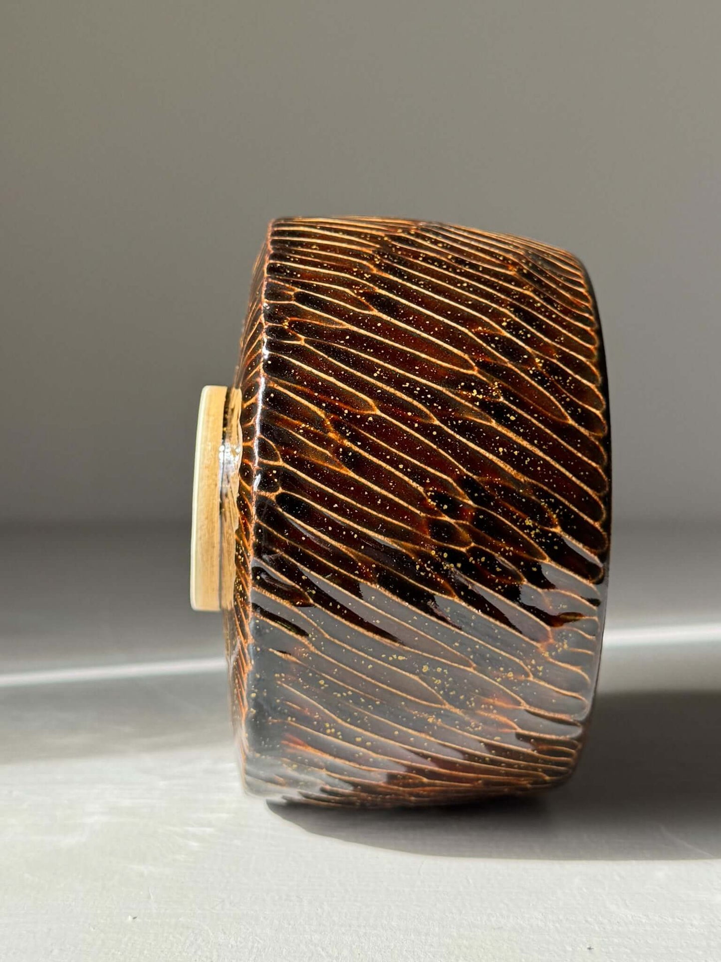 Handmade ceramic Matcha Bowl – Kinsei #05 with glossy brown exterior and gold spiral design, showcasing unique craftsmanship.