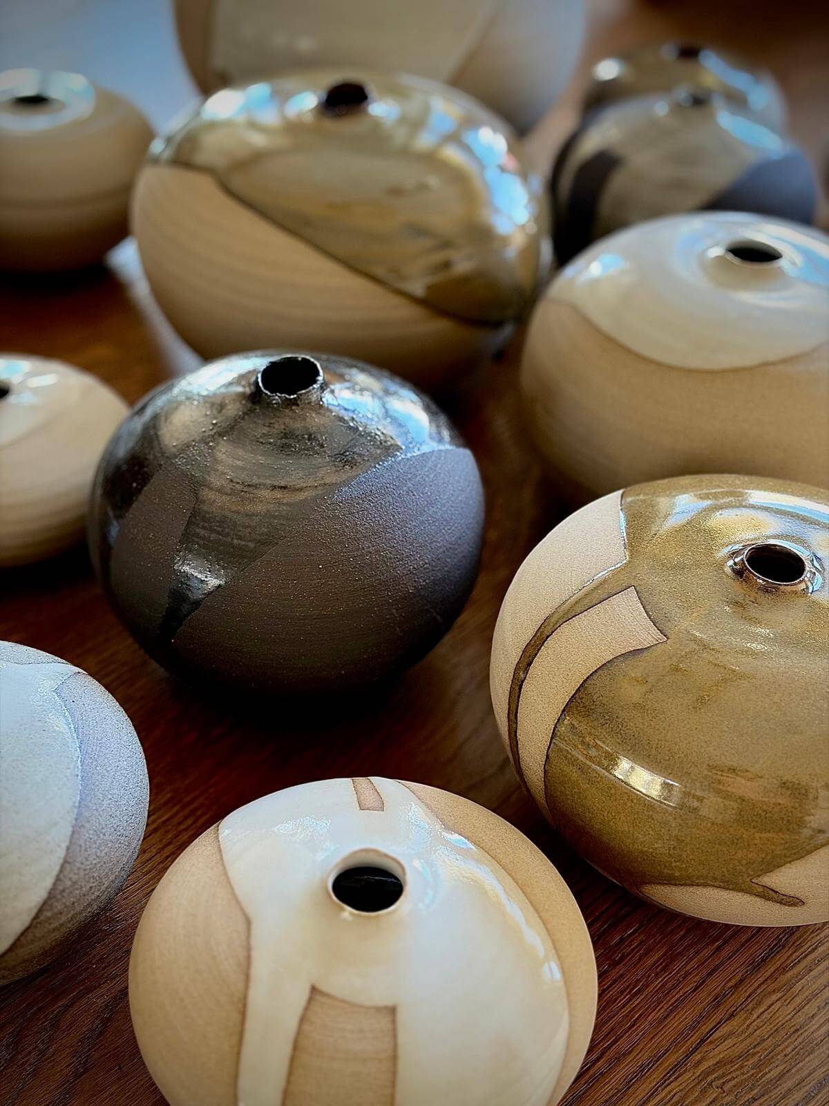 Orb Vase – Tenmoku #08 handmade ceramics with natural glaze patterns and rounded shapes on wooden table.