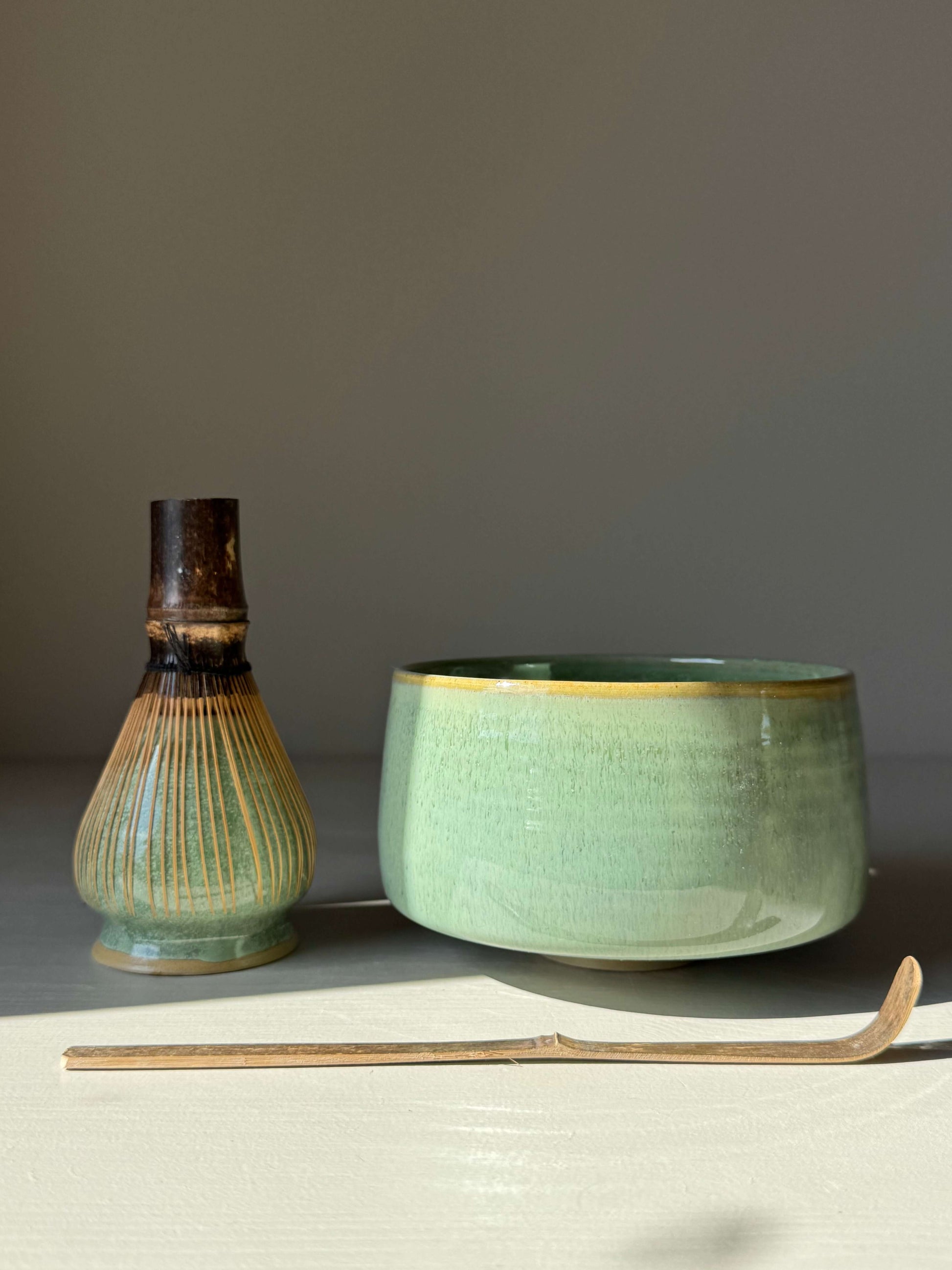 Handmade ceramic Matcha Bowl – Sage Glaze with bamboo whisk and chashaku, featuring a soft green gloss and golden rim accent.