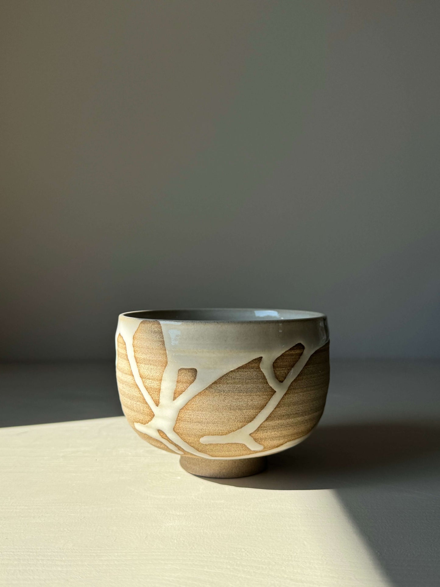 Handmade Matcha bowl from Yuki Series #01 with toffee clay and glossy white glaze, uniquely wheel-thrown and glazed; calm and aesthetic design.
