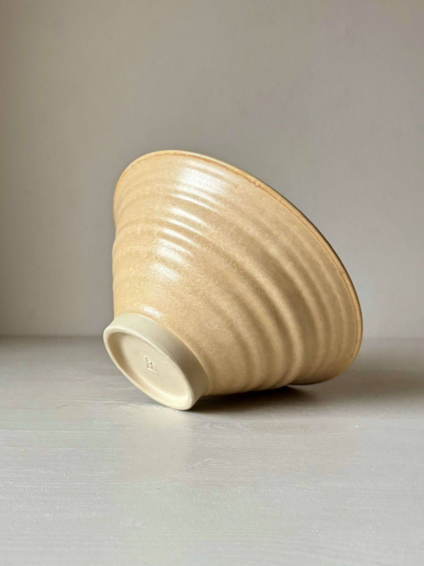 Handmade peach glazed stoneware candlestick holder, wheel-thrown, showcasing unique craftsmanship and delicate ceramics design.