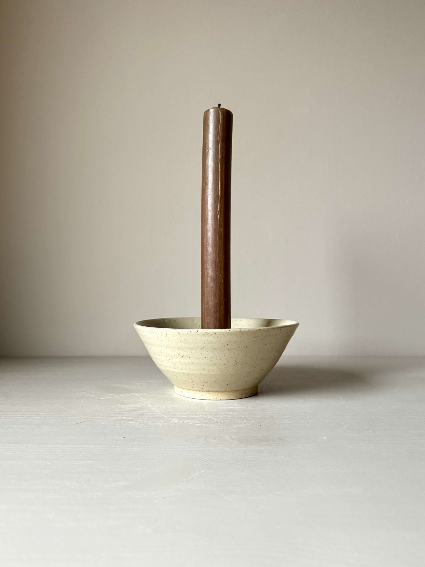 Handmade stoneware candlestick holder with clear glaze, 7cm height, 17.5cm diameter, featuring iron oxide spots.