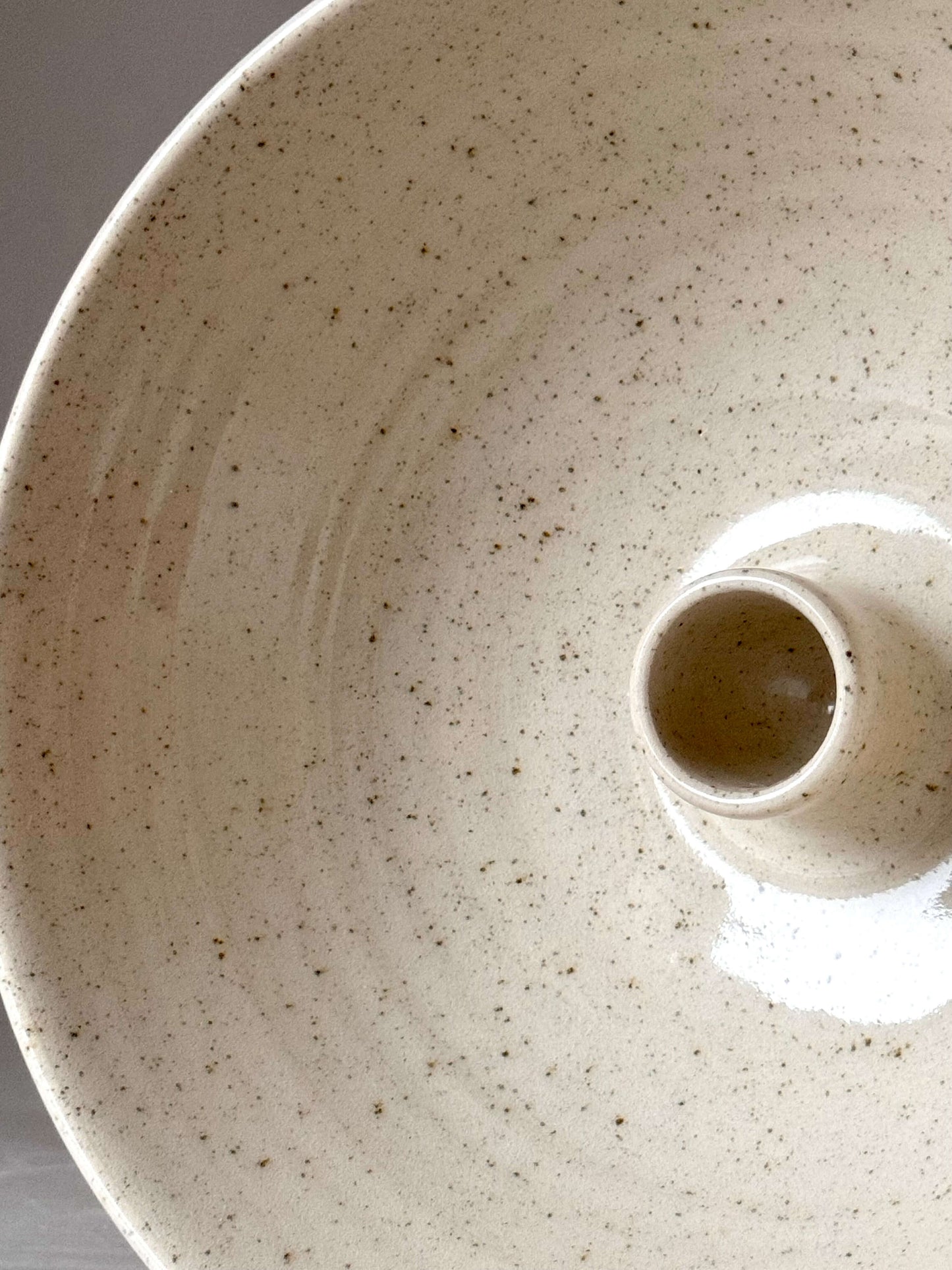 Handmade stoneware candlestick holder with clear glaze and iron oxide spots, wheel-thrown, unique design, perfect for home decor.