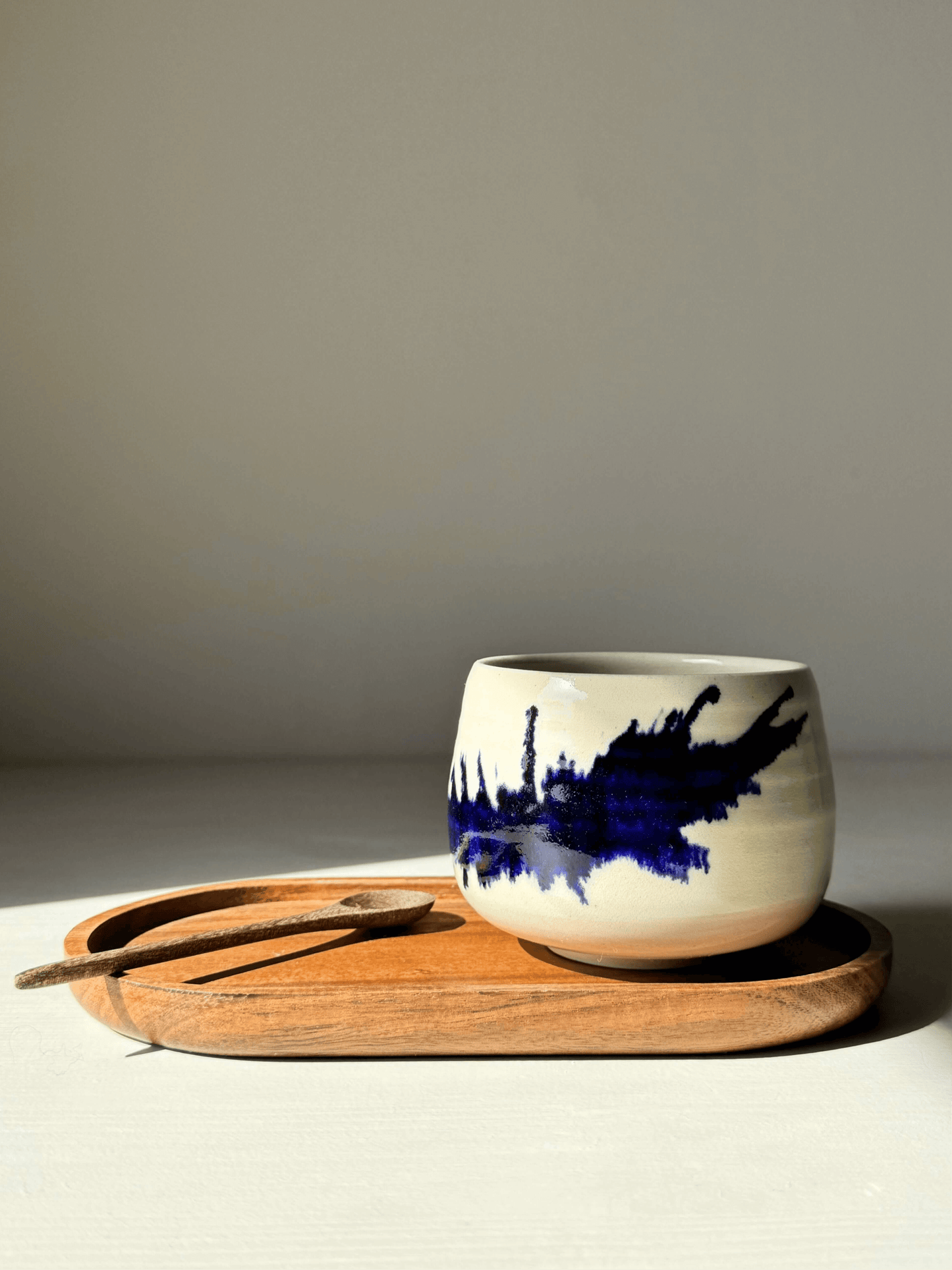 Gosu Series handmade ceramic coffee cup with cobalt blue splashes on a wooden tray, showcasing unique design and style.