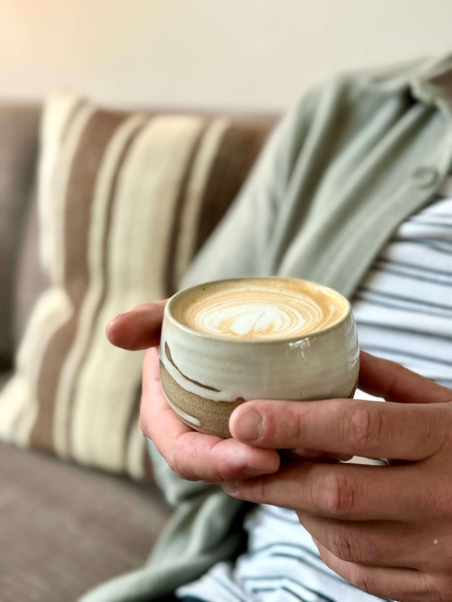 Handcrafted Coffee cups - Yuki series in ceramic with toffee clay and white glaze, held for comfort and warmth.