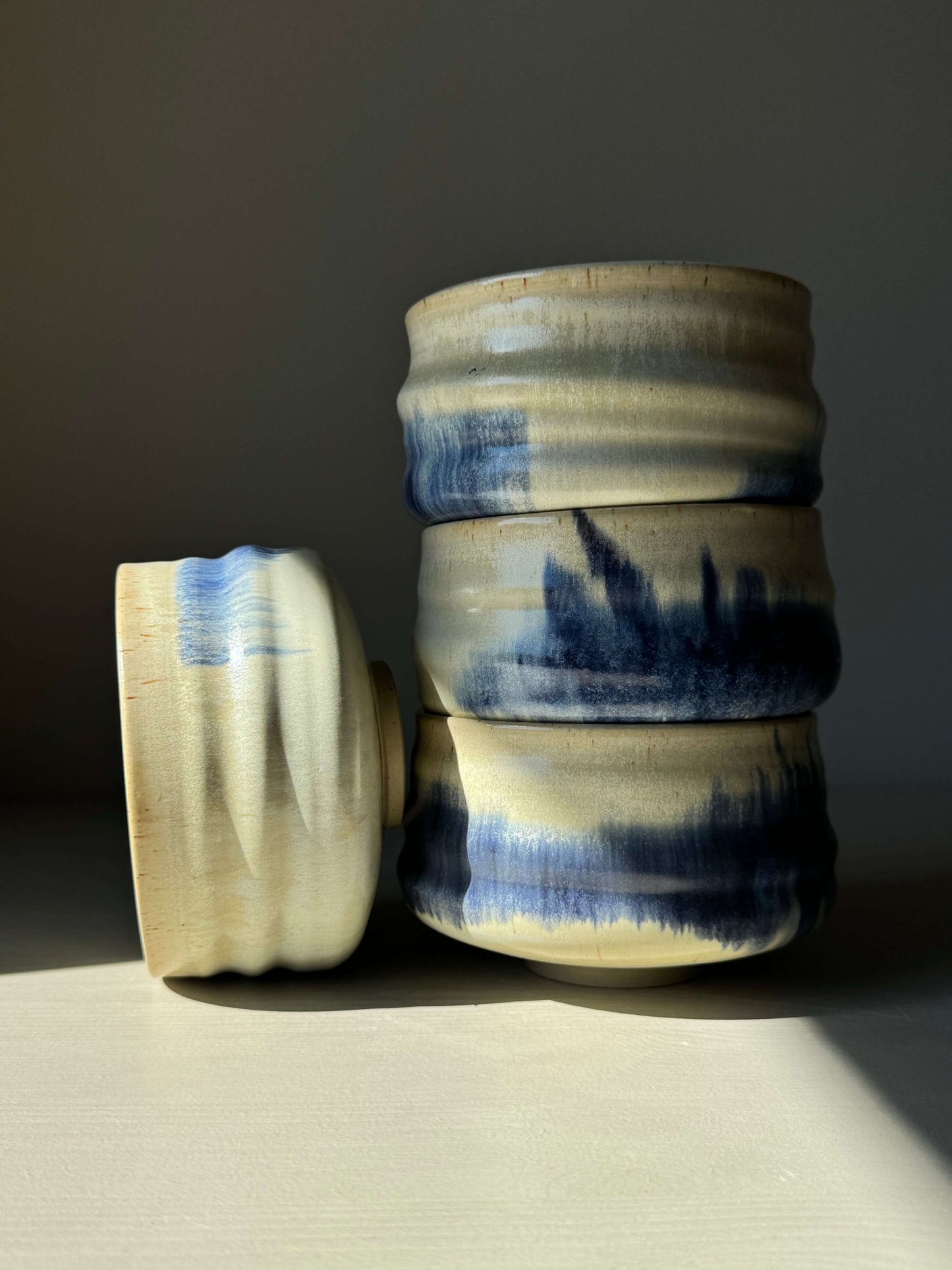Stack of handcrafted Matcha bowls with cobalt blue and moonstone glaze, showcasing unique splatter design on ceramic surface.