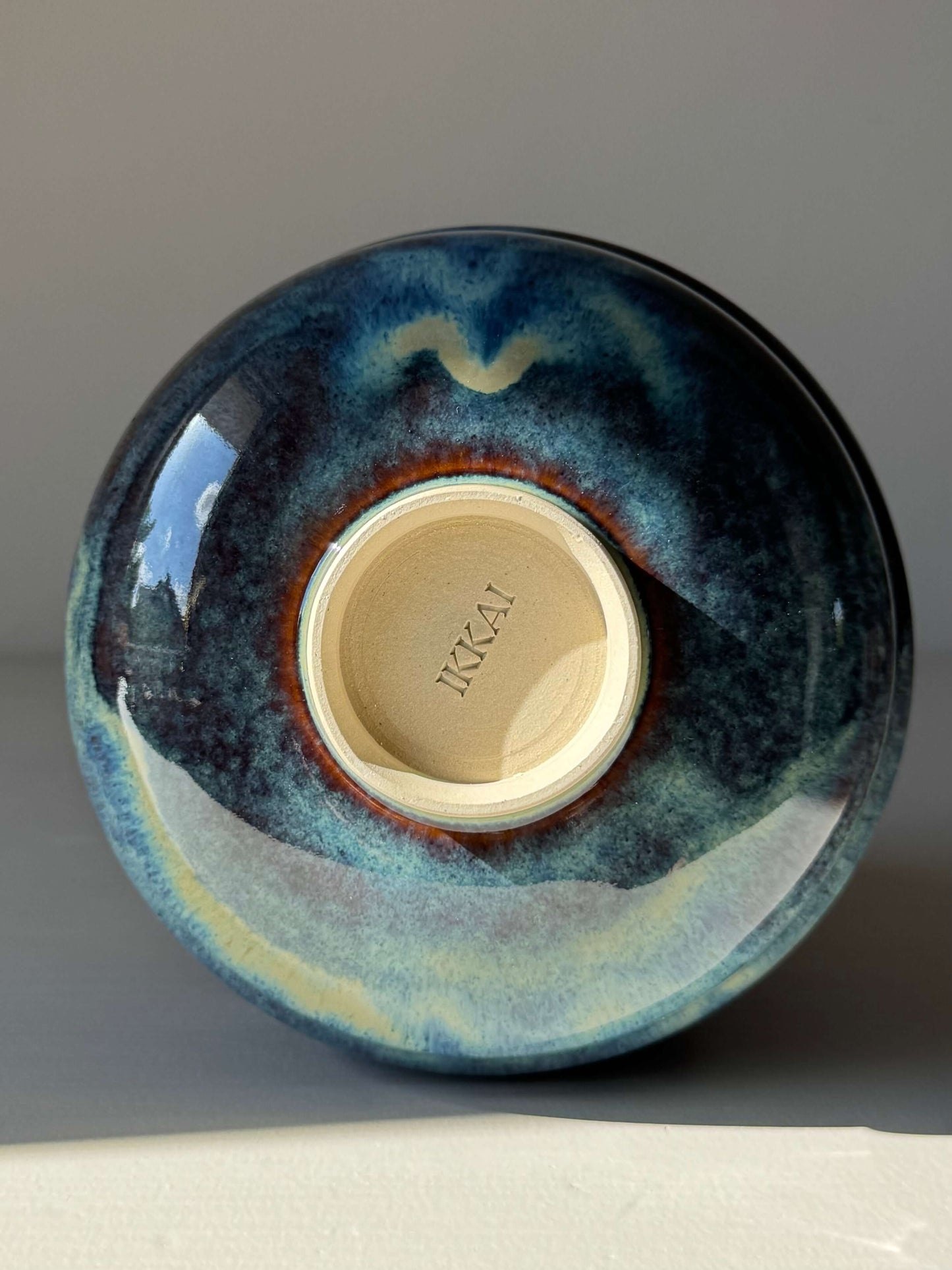 Matcha Bowl - Glossy Blue #02, handmade ceramic with earthy tones, displaying unique flowing blues and raised foot design.