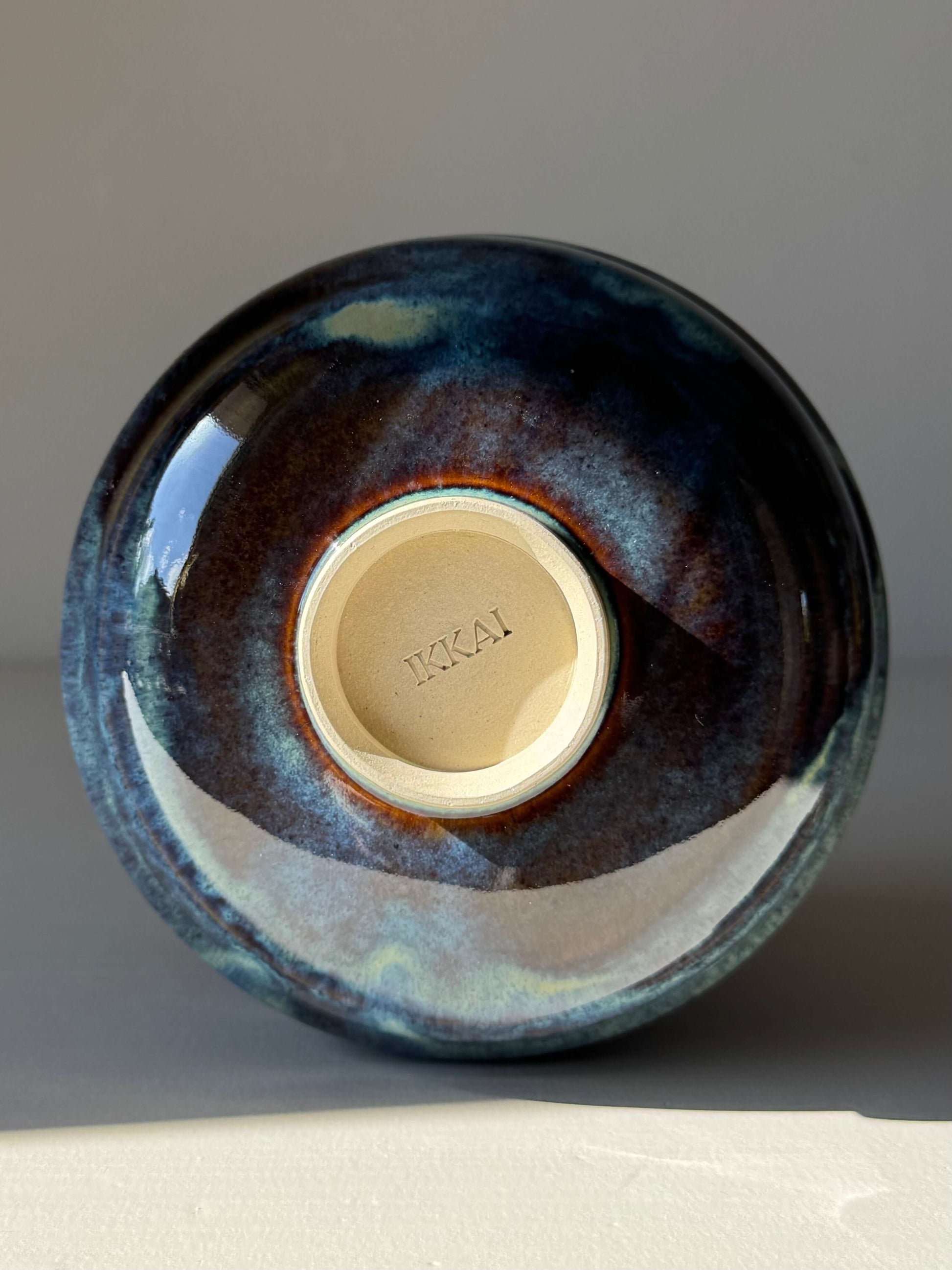 Handmade ceramic Matcha Bowl - Glossy Blue #03 with earthy and flowing blue tones, view of bottom raised foot, approx. 7.5cm height.