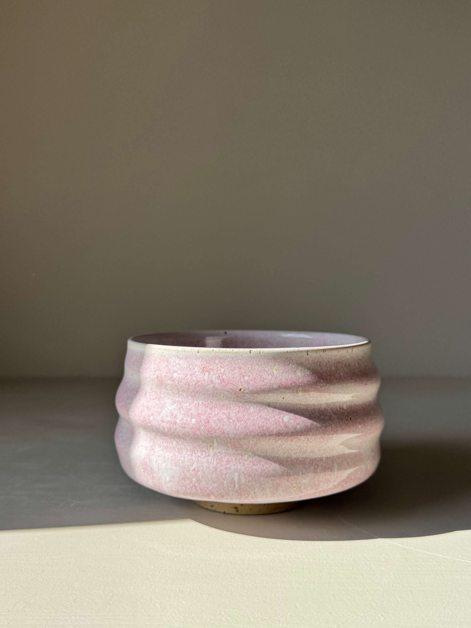 Handmade ceramic Matcha Bowl - Pale Pink with soft glaze and sculpted ridges, under soft light.