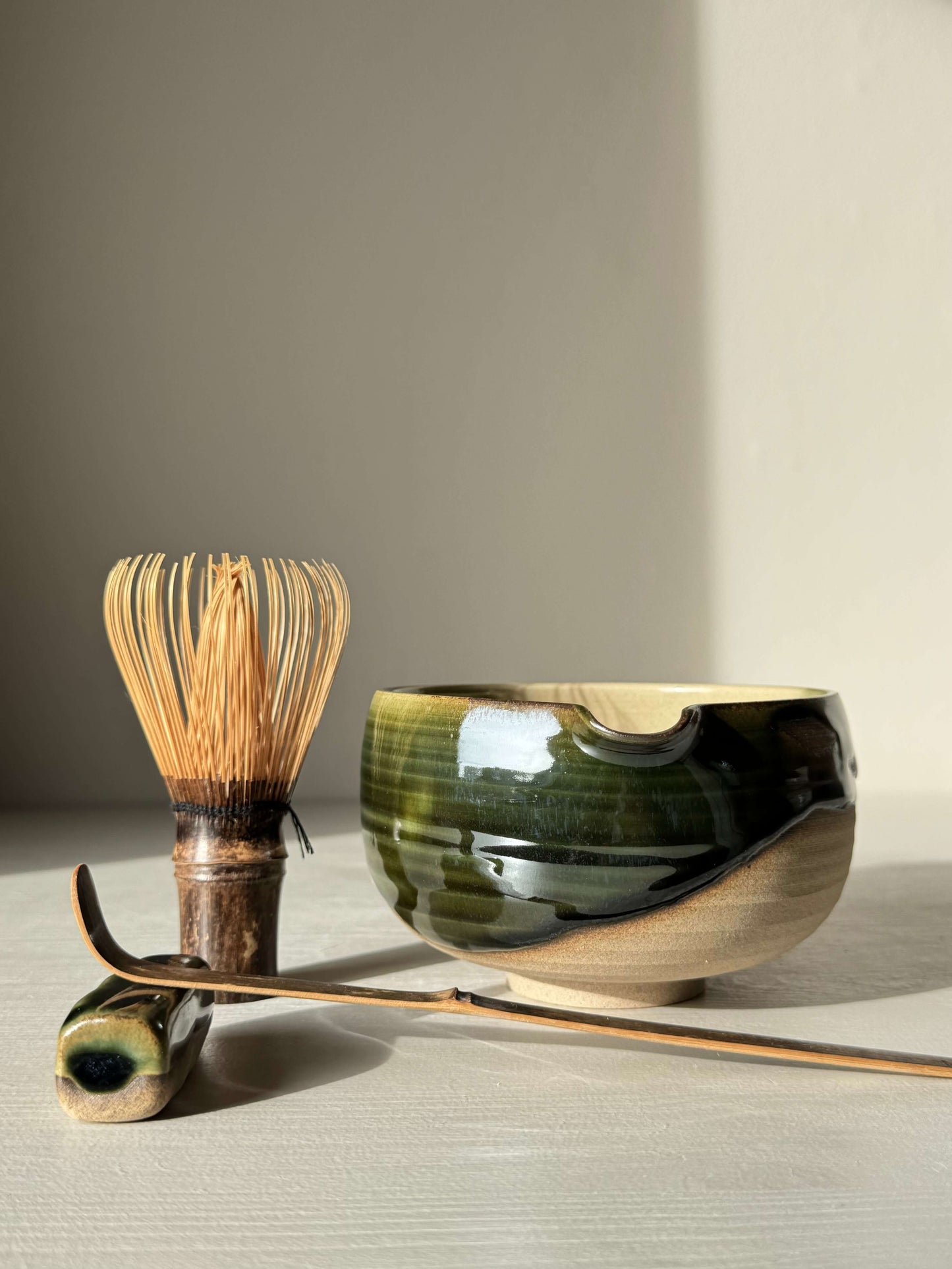 Handmade ceramic Matcha Bowl with Spout – Mori #06 in green and brown glaze, part of Mori Series, with tea accessories.