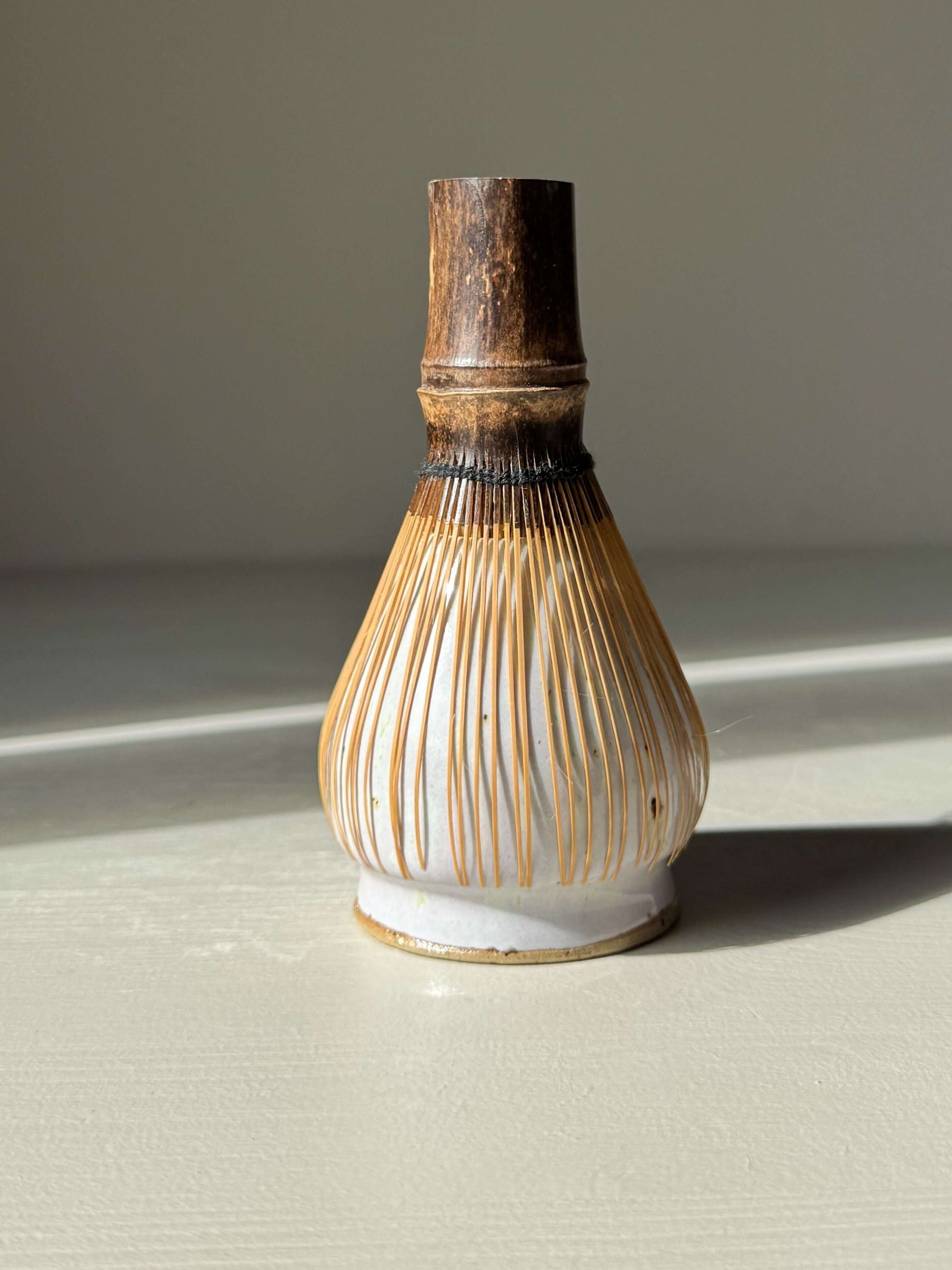 Matcha Whisk Holder - Pale Lilac, handmade ceramic, supporting a traditional bamboo whisk on display.