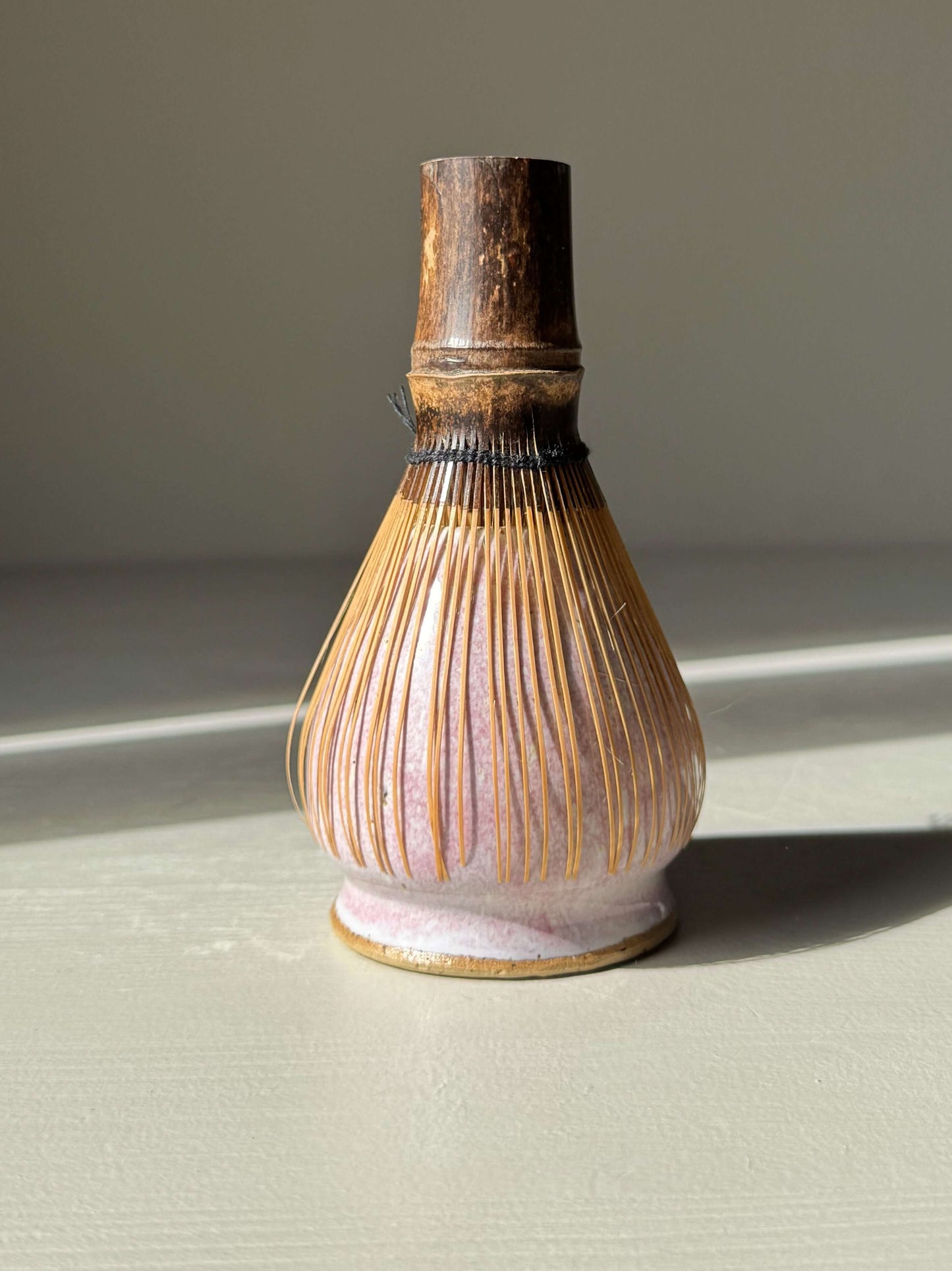 Matcha Whisk Holder - Pale Pink handmade ceramic in sunlight, highlighting its unique color and texture.