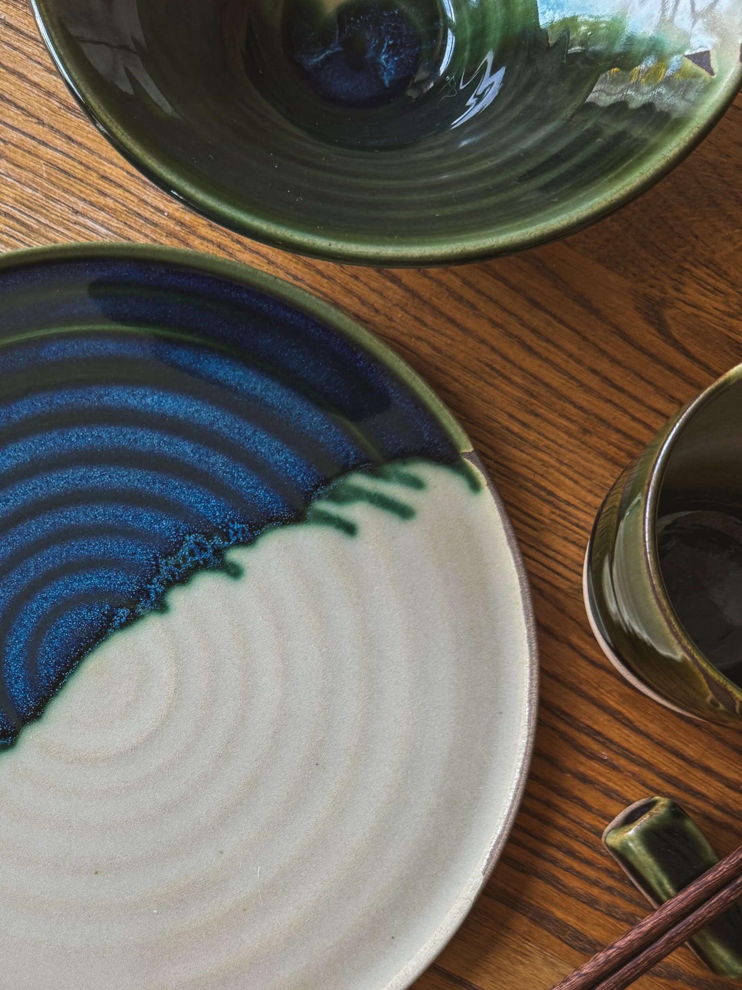 Handmade ceramic Flat Round Plate – Mori with green and clear glaze on wood table.