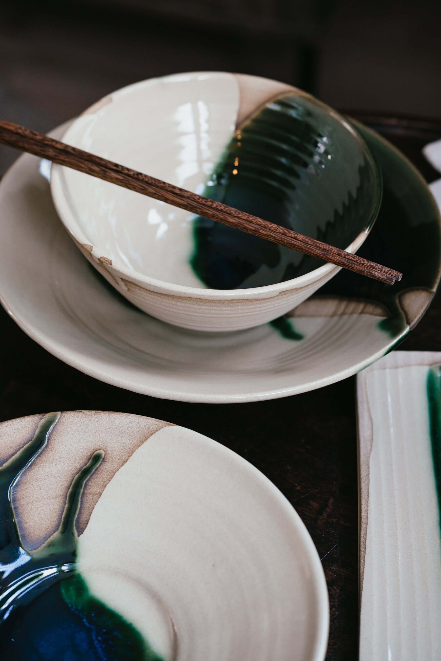 Ramen Bowl - Mori handmade ceramic bowl with green glaze on a plate, showcasing artistic craftsmanship.