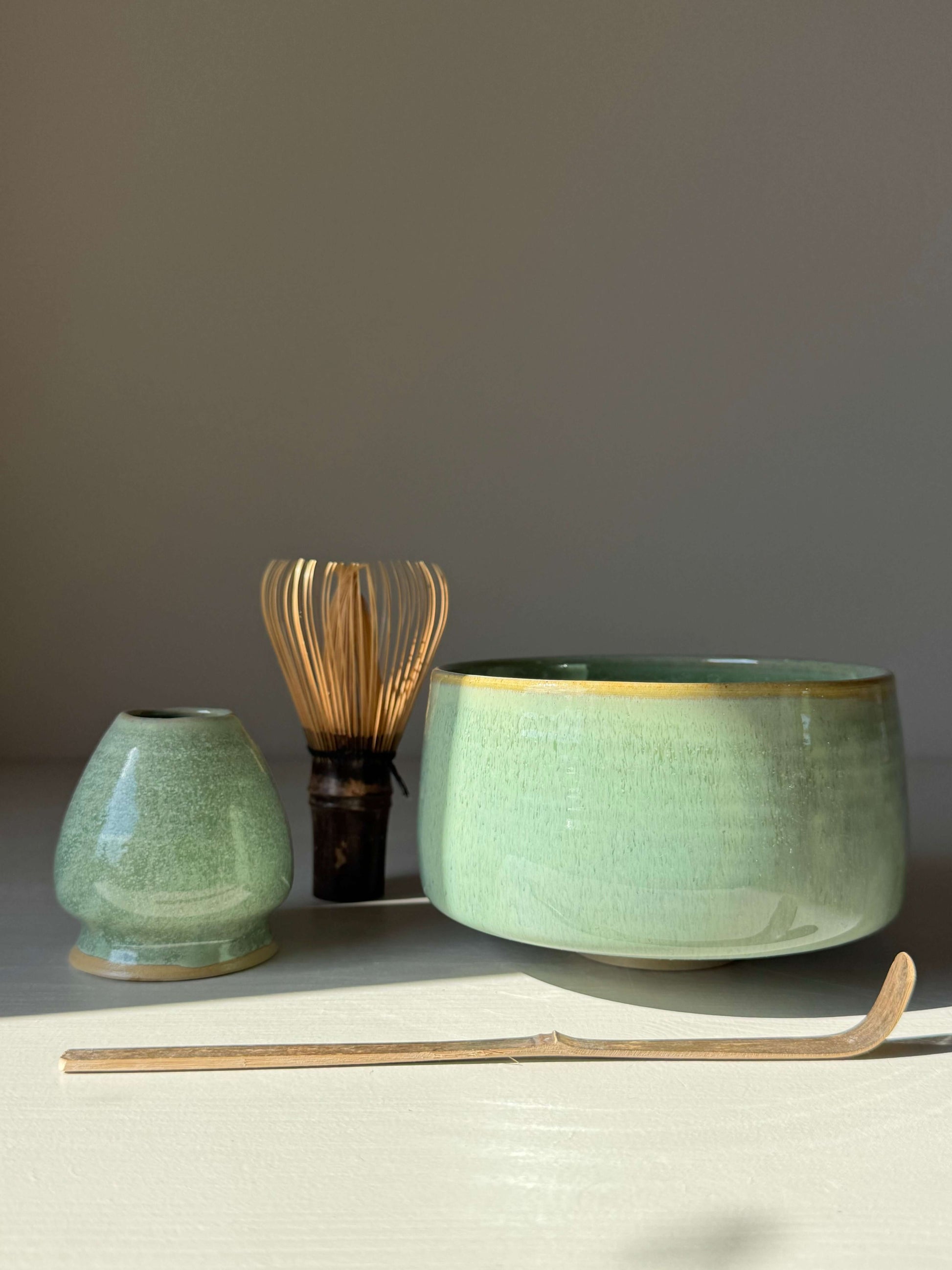 Handmade ceramic Matcha Bowl – Sage Glaze with glossy sage finish, golden rim, and whisk, perfect for smooth and frothy matcha preparation.