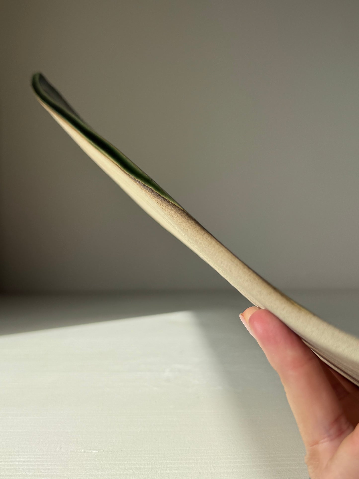 Side view of handmade ceramic Sushi Plate – Mori Series #01 showing its unique flat design and green glaze details.