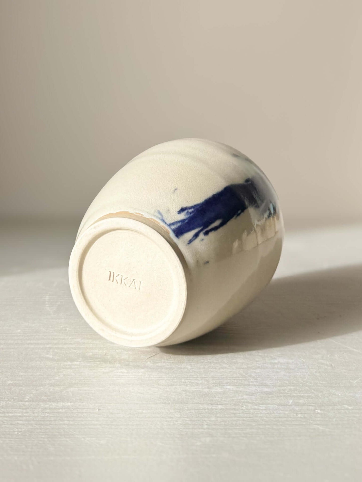 Ceramic Vase - Gosu #06 lying on its side, showcasing hand-splashed cobalt blue accents and glossy clear glaze, unique modern design.