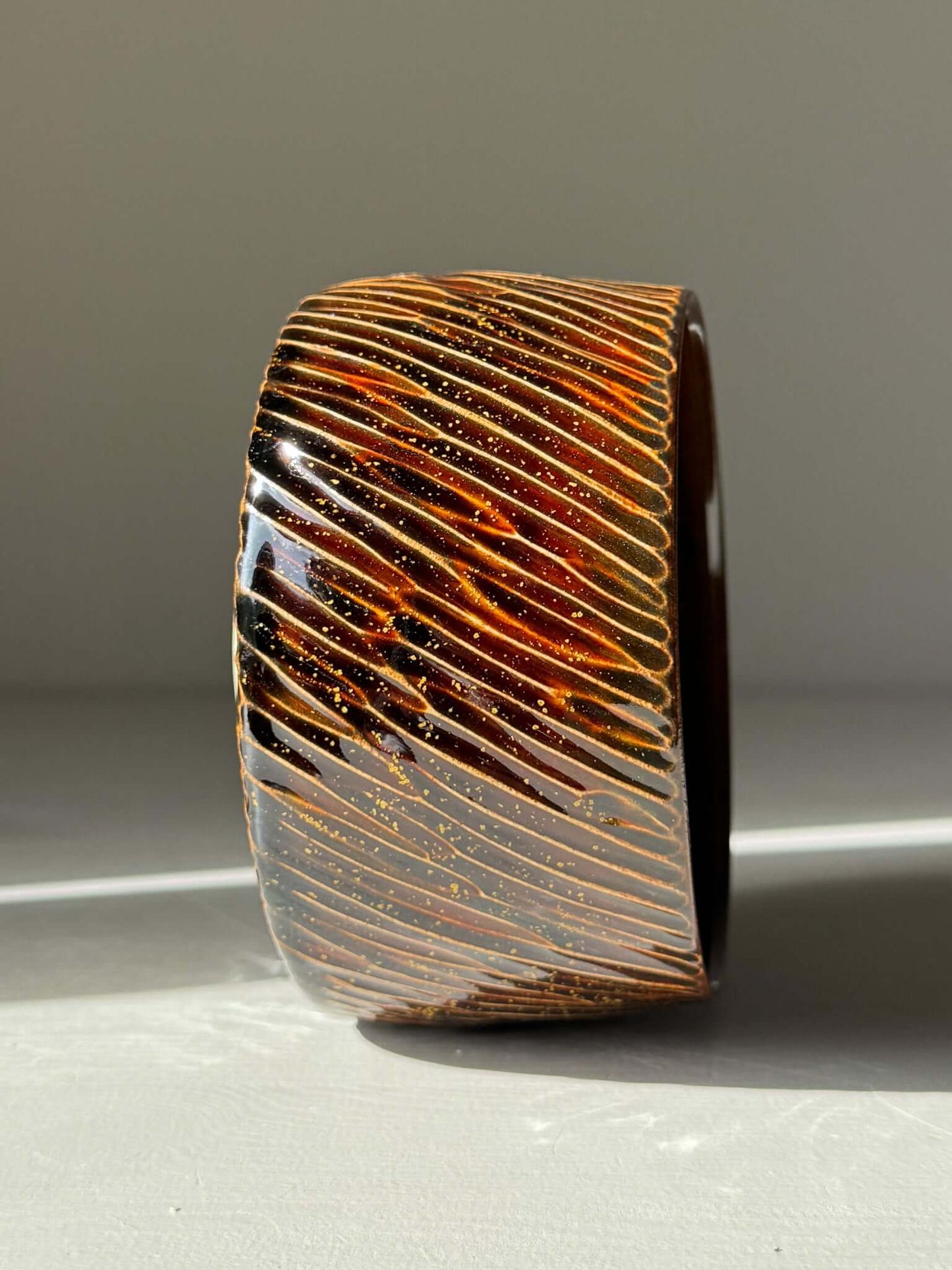 Handmade ceramic Matcha Bowl – Kinsei #04 with glossy brown exterior and spiral of gold and orange, glowing like a star.