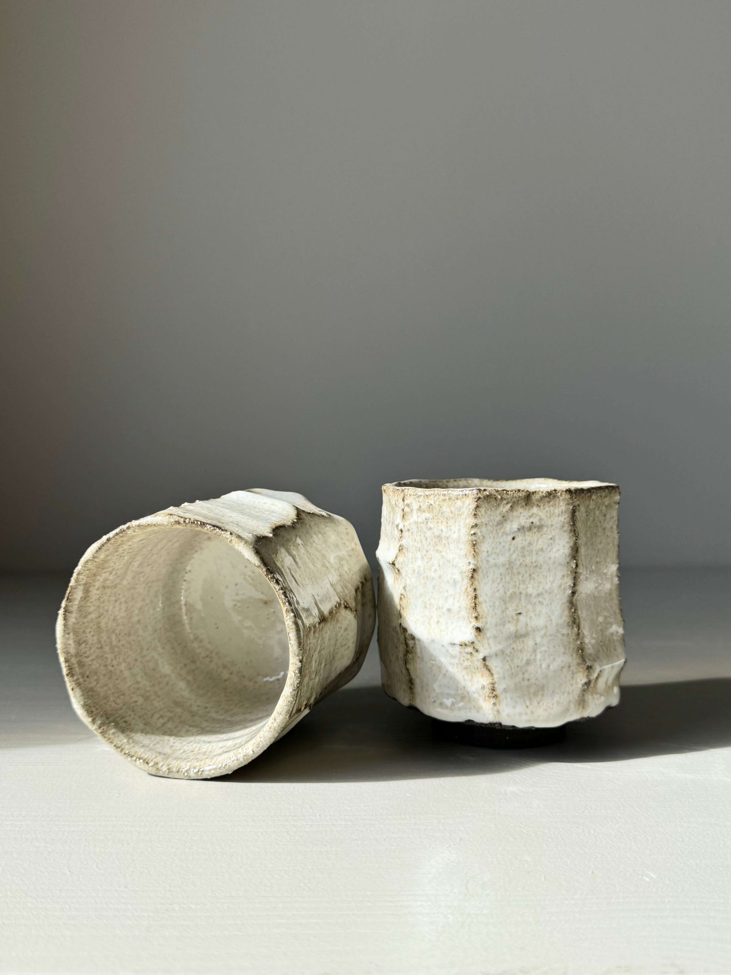 Kurinuki style cups with nuka glaze, showcasing hand-carved textures and creamy finish, embodying raw, earthy craftsmanship.