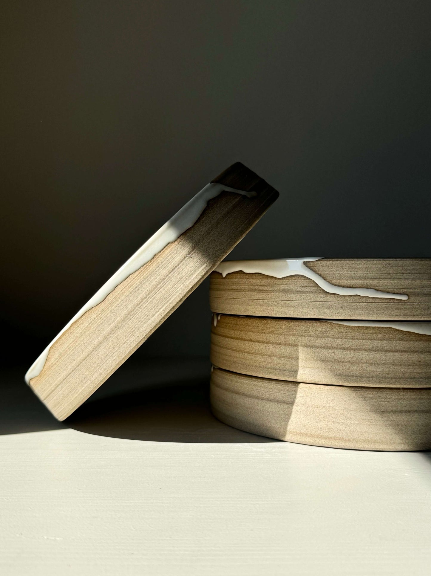 Handmade ceramic stack with glossy white glaze, showcasing the Large Plate – Yuki Series in soft light and earthy tones.