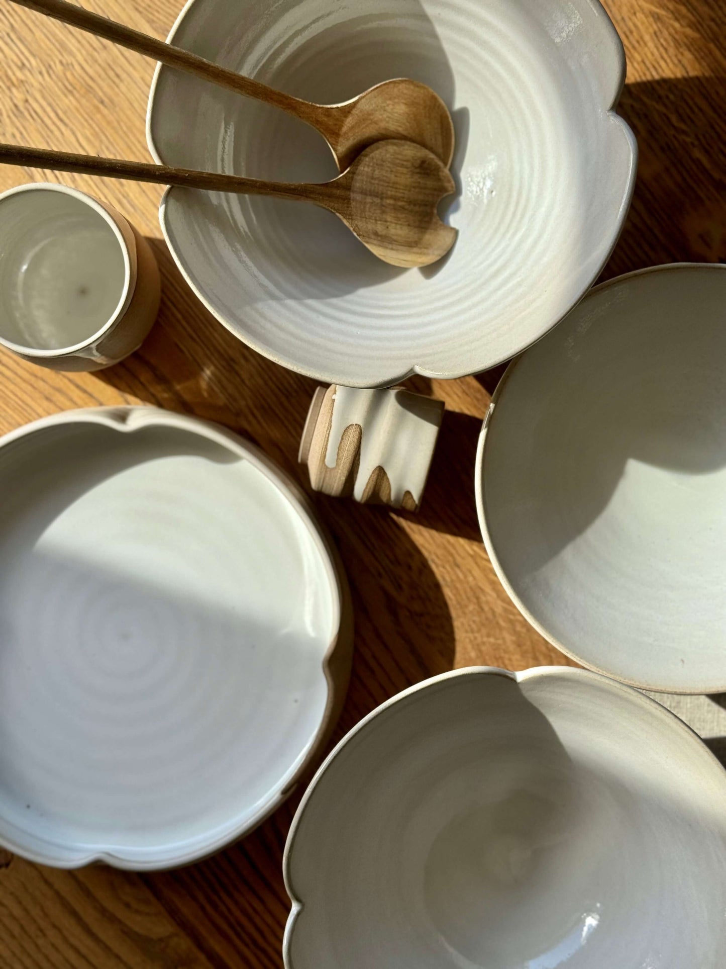 Elegant Yuki Series stoneware plates with scalloped rims and glossy white glaze, inspired by blooming flowers, on a wooden surface.