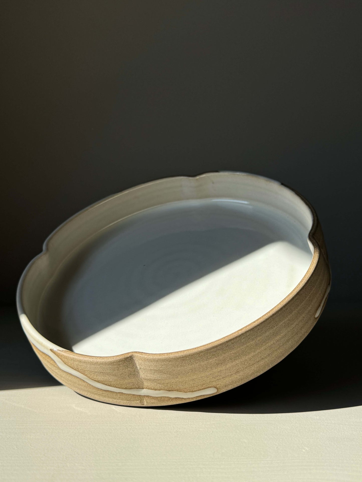 Large Flower Plate from Yuki Series featuring scalloped rim, glossy white glaze, and toffee-colored clay exterior, inspired by blooming flowers.