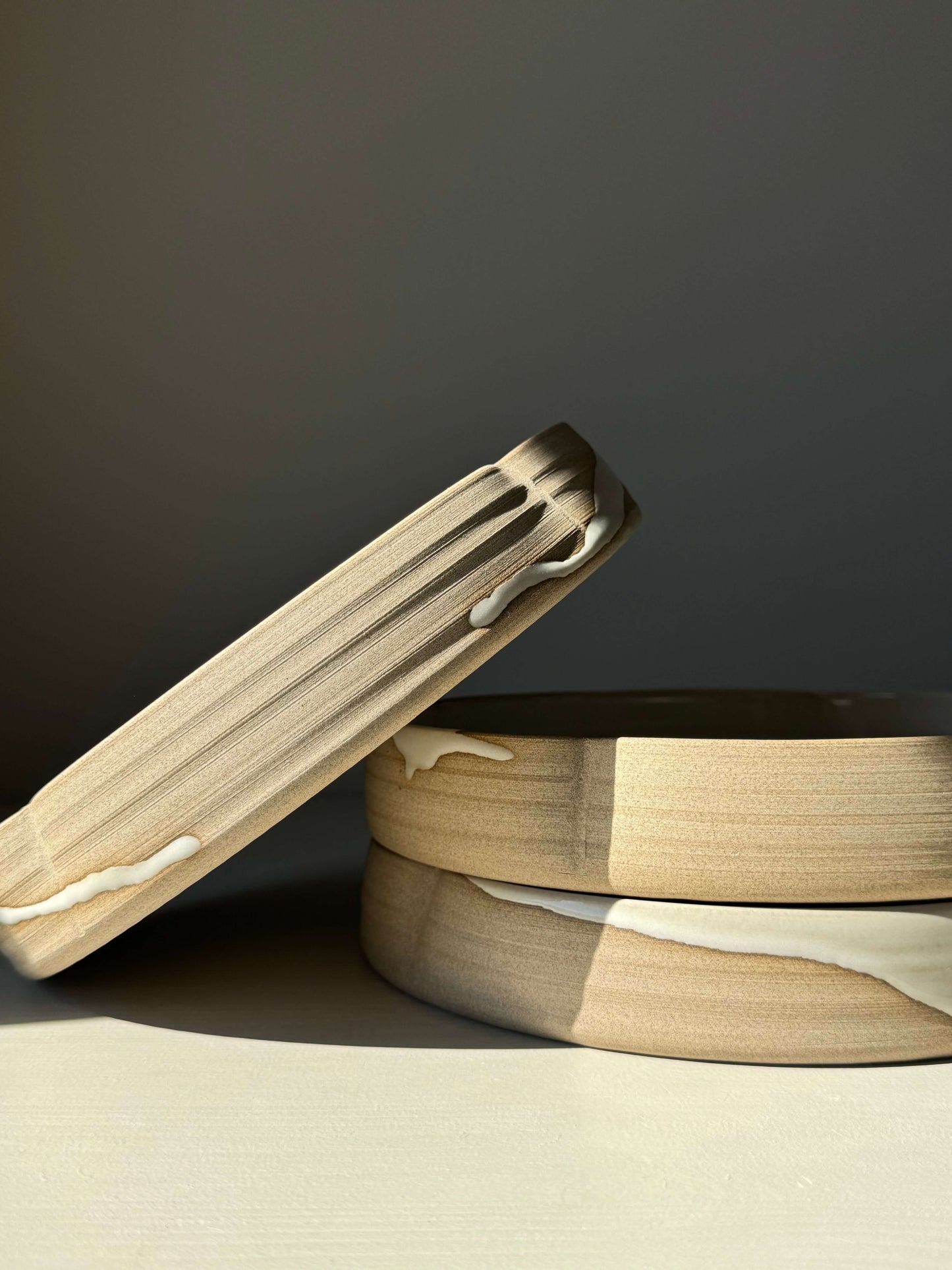 Stack of wooden bowls with artistic white drip glaze, showcasing unique handcrafted design and natural wood texture.