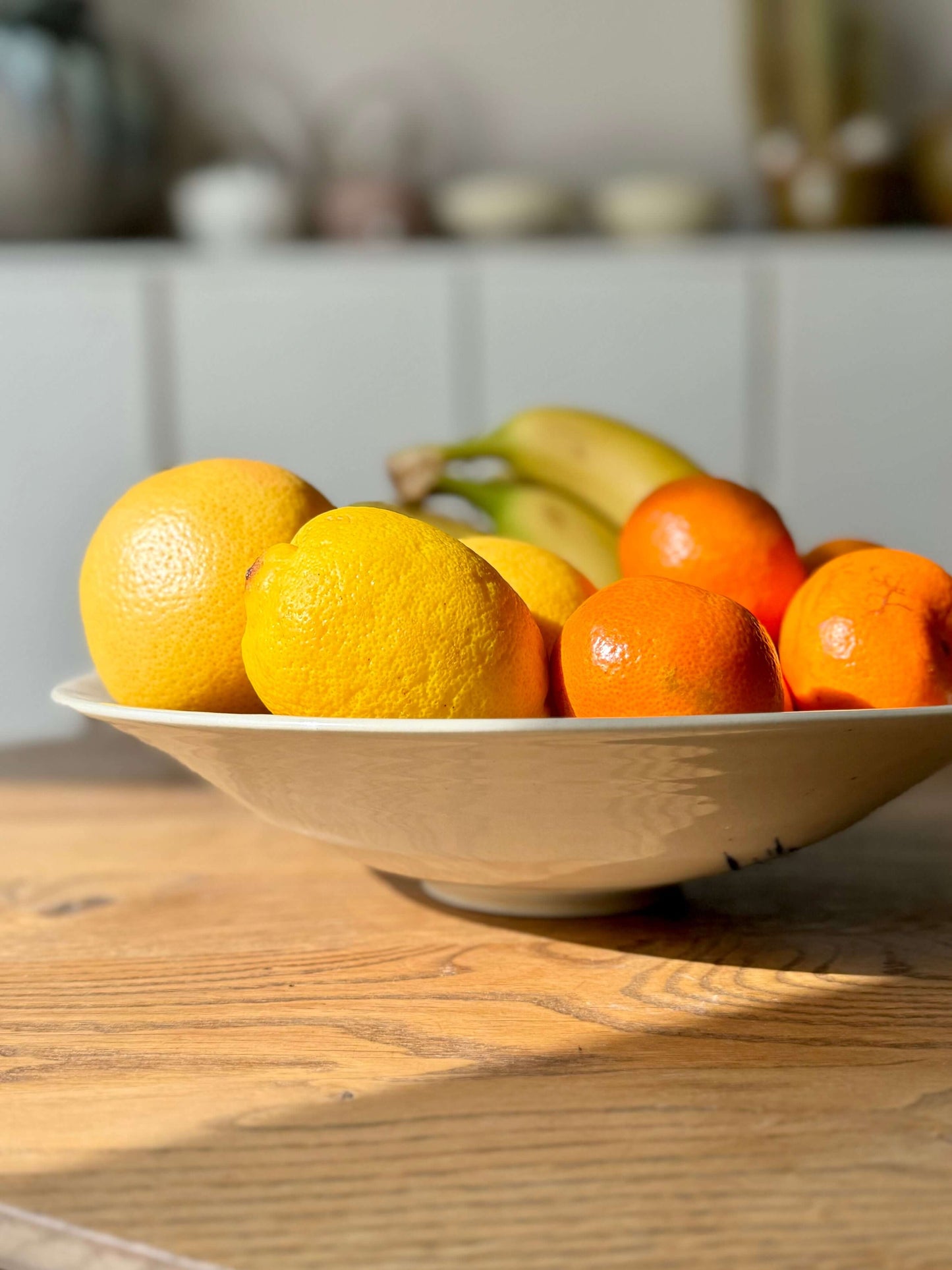 Large shallow bowl from Gosu Series #04 holding citrus and bananas, made from durable stoneware clay.