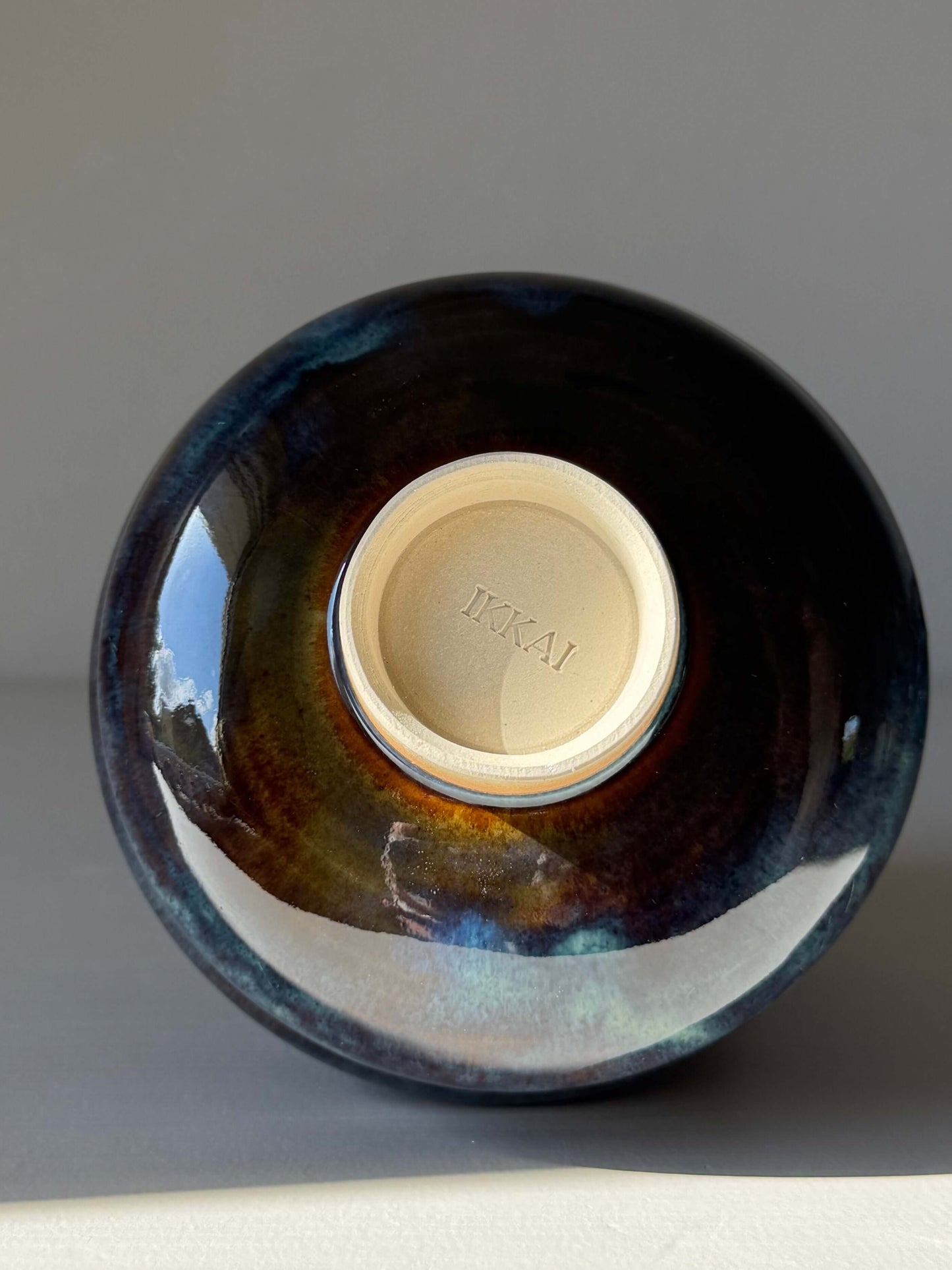 Matcha Bowl - Glossy Blue #04 showcasing its unique handmade ceramic base with deep earthy tones and flowing blues.