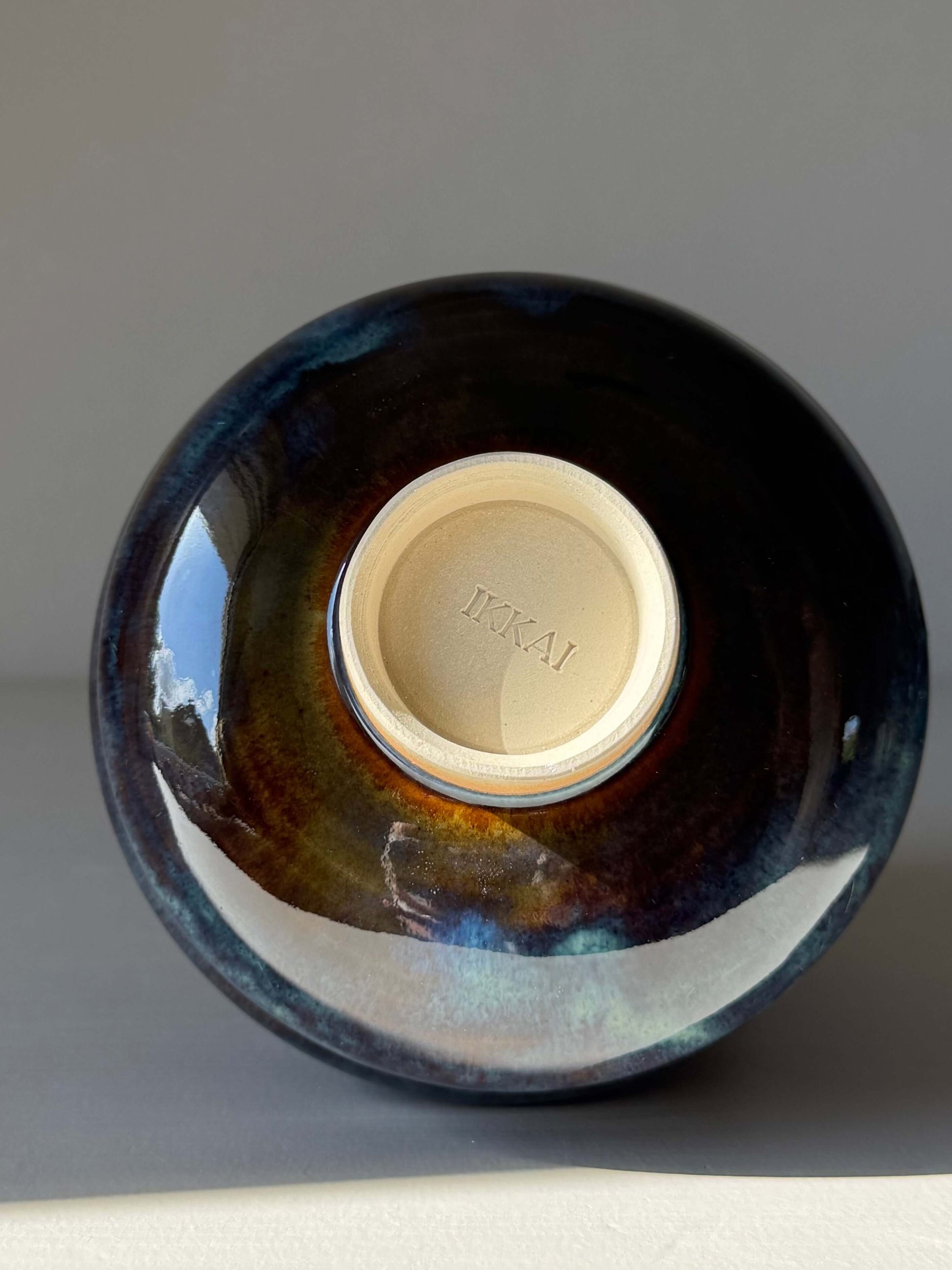 Matcha Bowl - Glossy Blue #04 showcasing its unique handmade ceramic base with deep earthy tones and flowing blues.