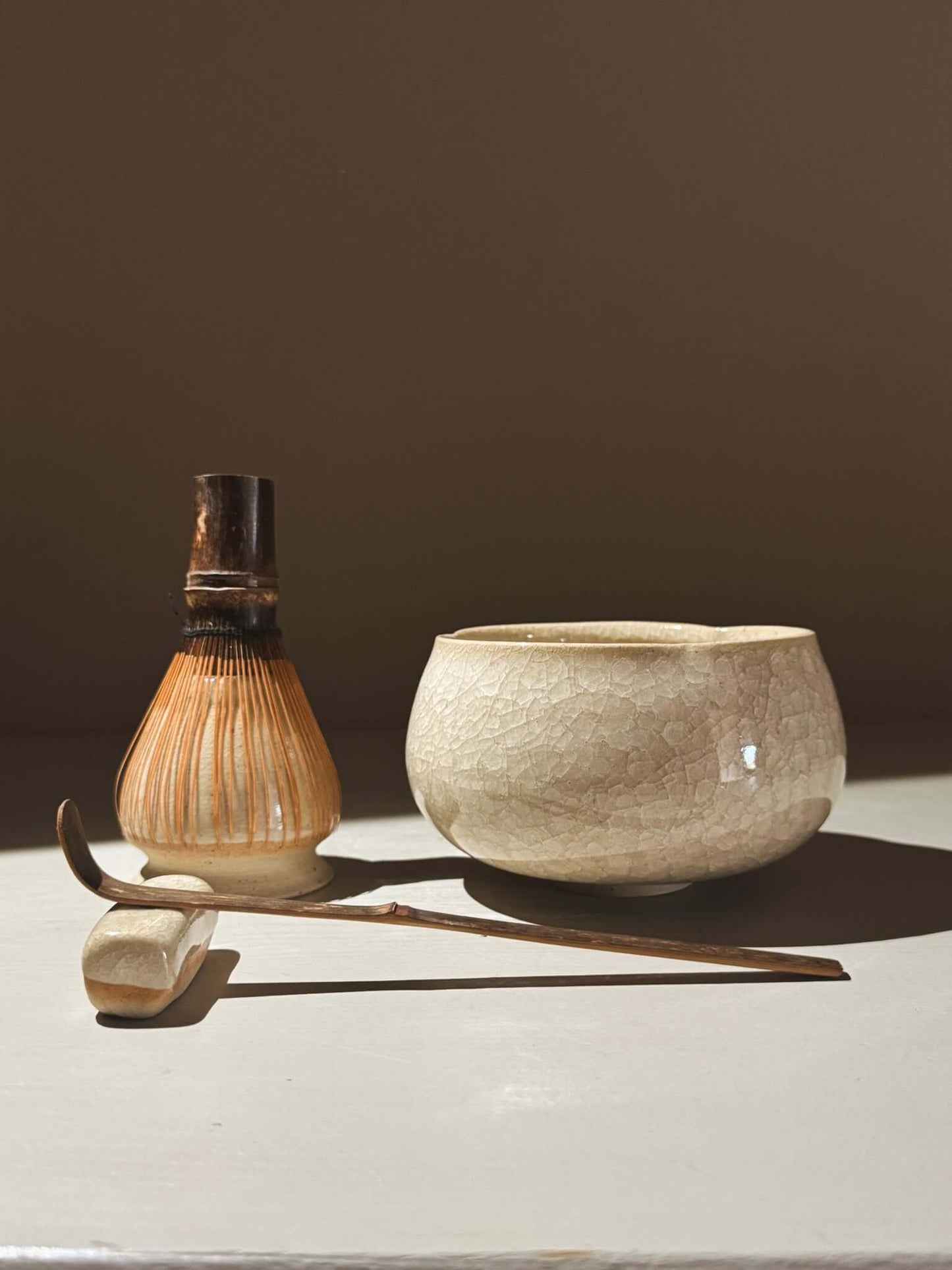Matcha Bowl - Kannyū #15 with whisk and scoop on a wooden table, featuring a crackle glaze and gentle shape.