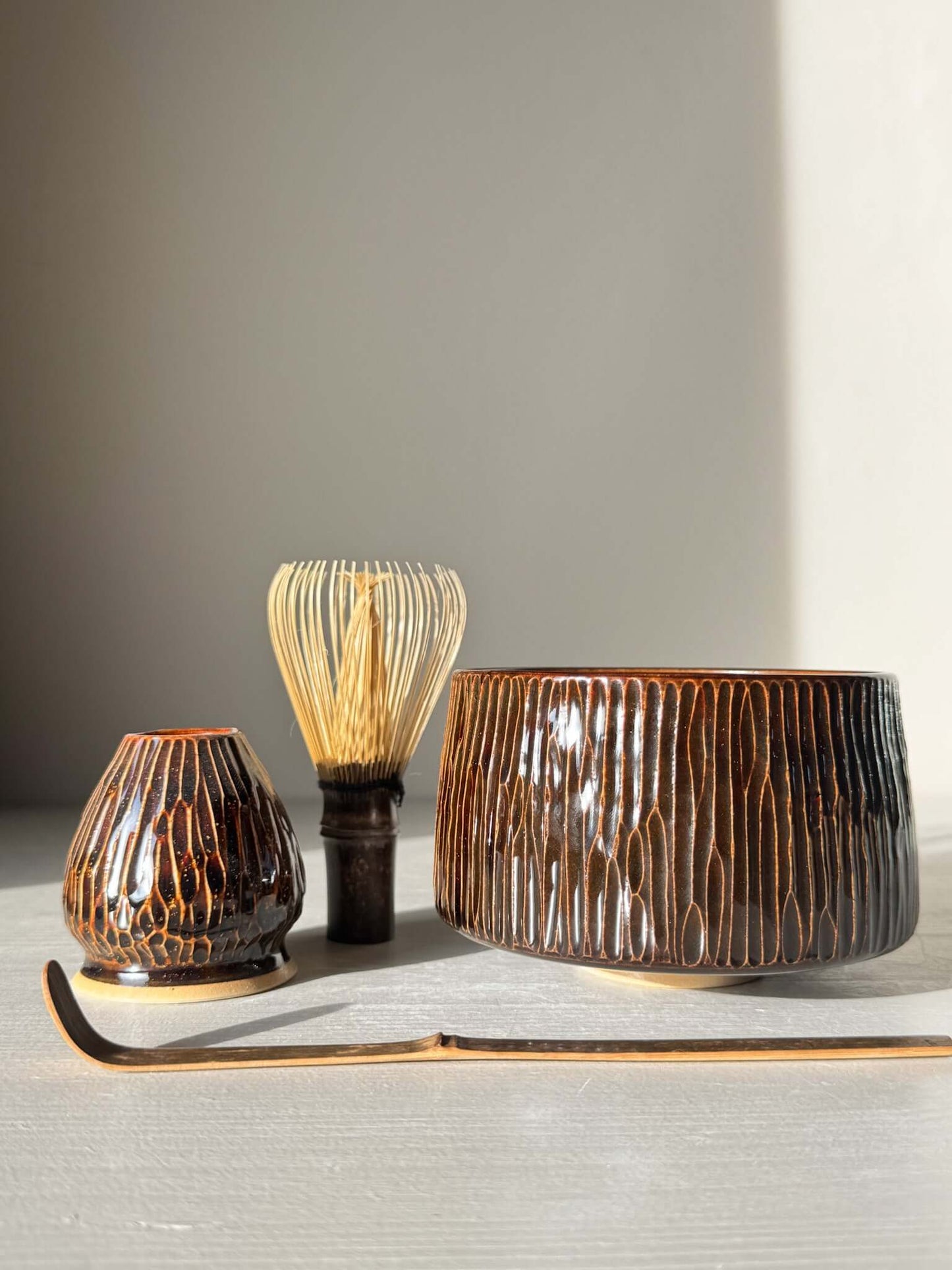 Matcha Bowl – Kinsei #01 with hand-carved lines and glossy swirl glaze, accompanied by utensils, highlighting artisanal craftsmanship.